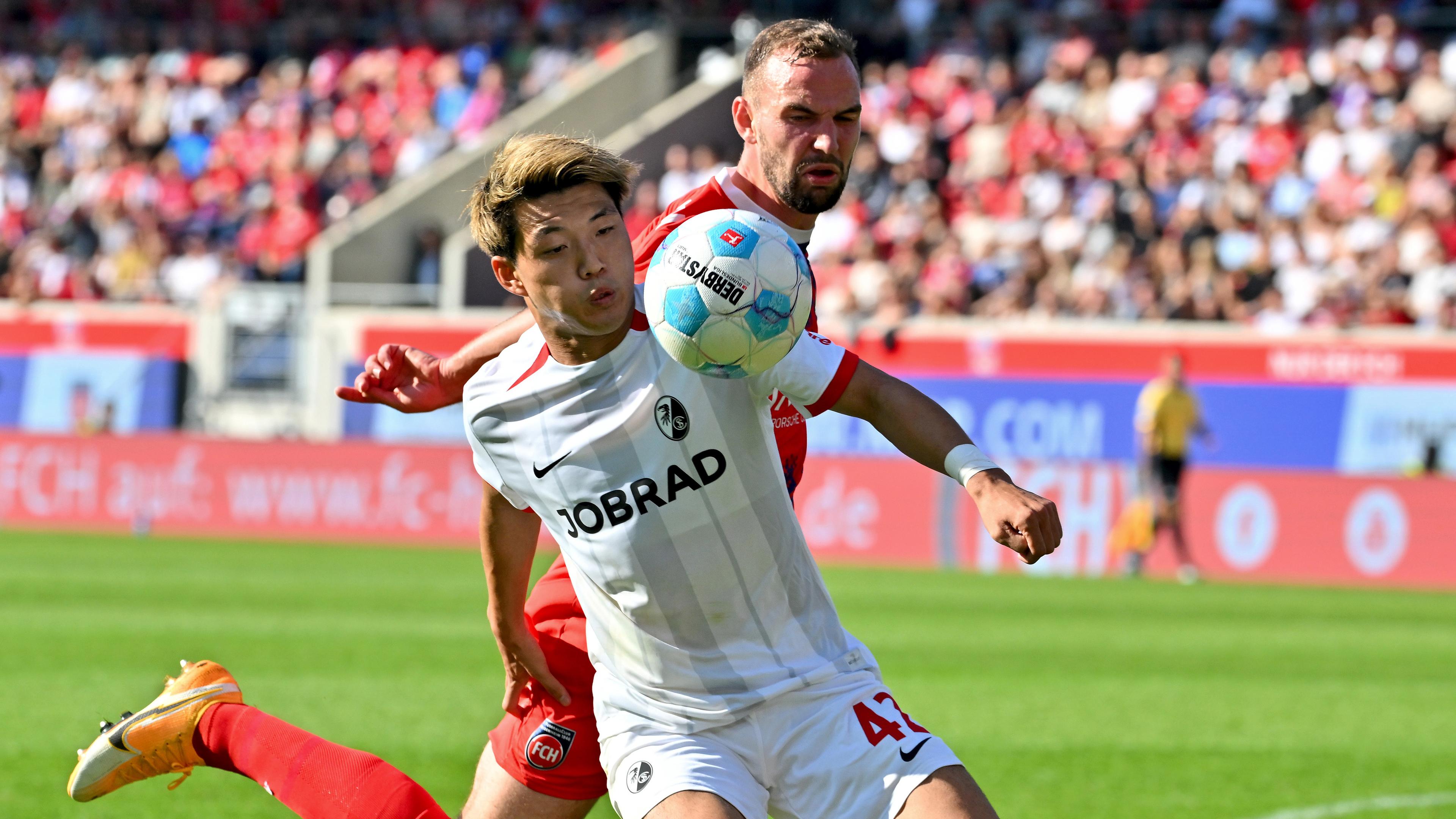 Ritsu Doan vom SC Freiburg im Zweikampf mit Heidenheims Benedikt Gimber.