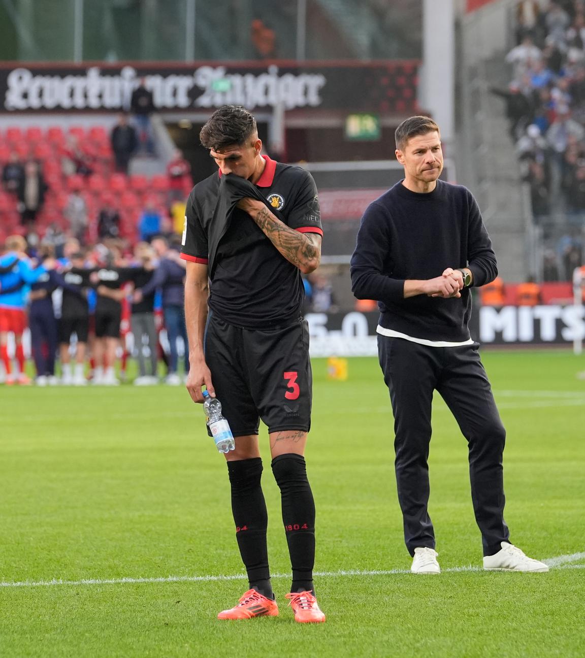 Trainer Xabi Alonso und Spieler des Bayer 04 Leverkusen stehen enttäuscht auf dem Rasen nach dem 2:2 Spiel gegen Holstein Kiel.