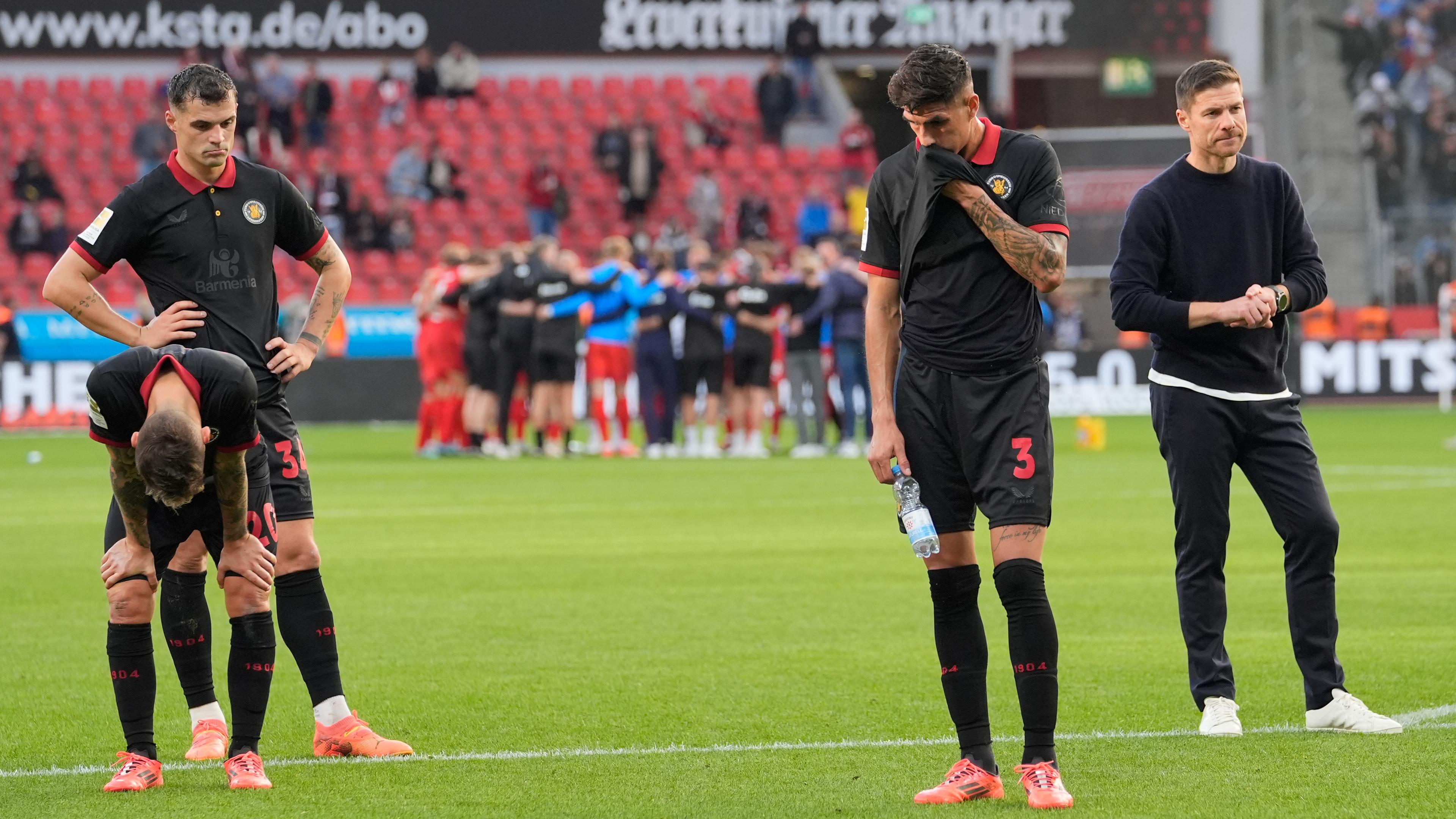 Trainer Xabi Alonso und Spieler des Bayer 04 Leverkusen stehen enttäuscht auf dem Rasen nach dem 2:2 Spiel gegen Holstein Kiel.