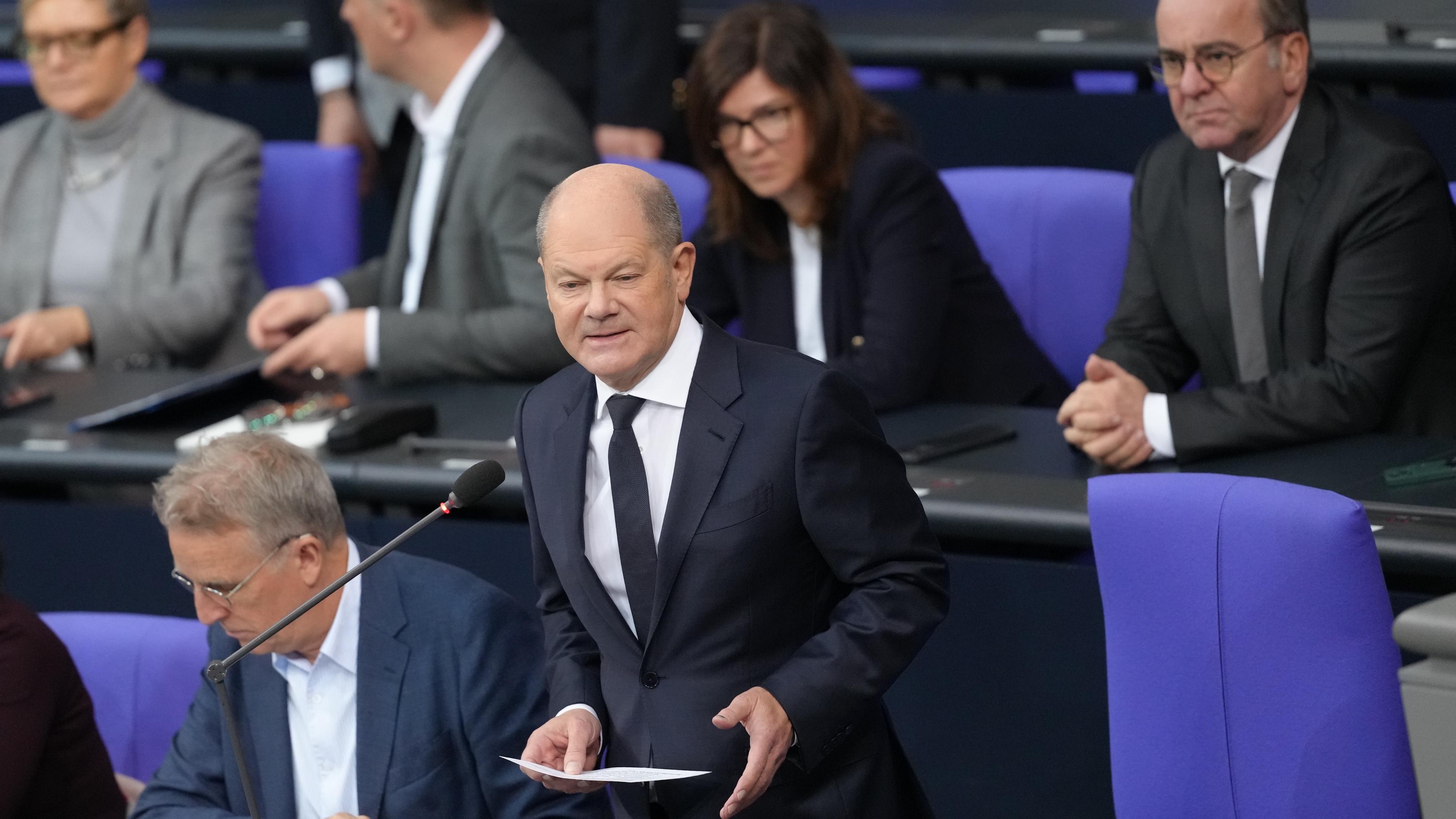 04.12.2024, Berlin: Bundeskanzler Olaf Scholz (SPD,r) nimmt an der Befragung der Bundesregierung im Plenarsaal im Bundestag teil.