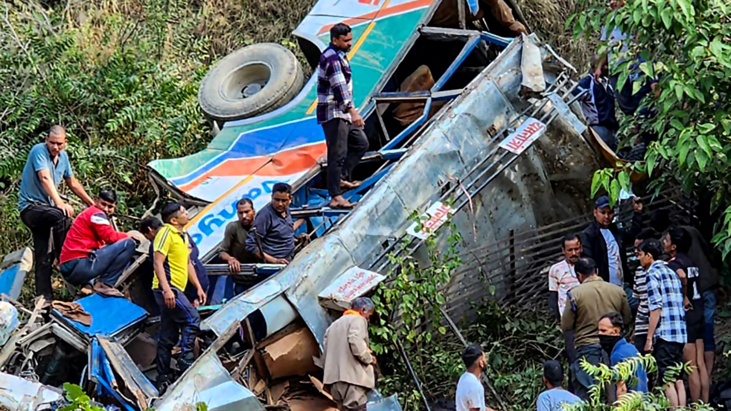 Menschen an der Unfallstelle eines Busses, der in eine Schlucht gestürzt ist.