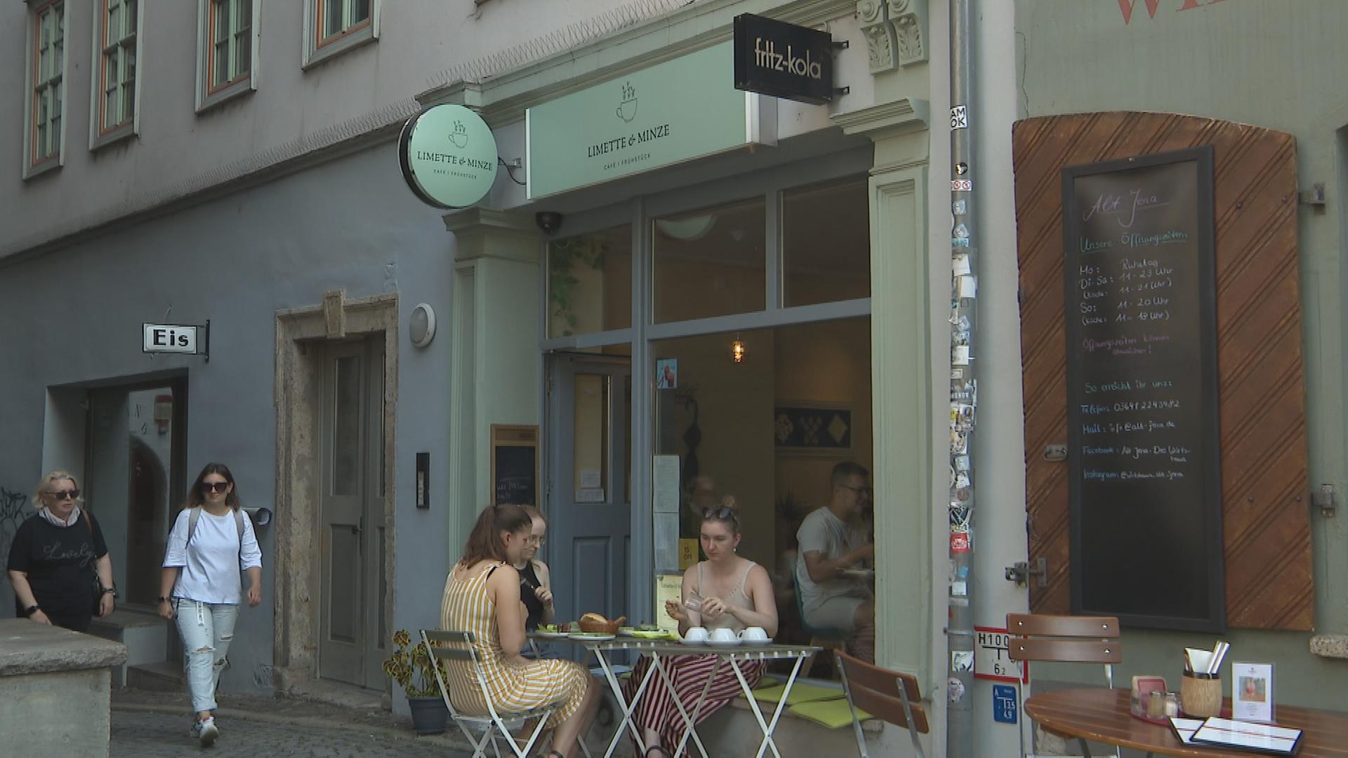 Drei Frauen sitzen an Tisch vor Café in Jena