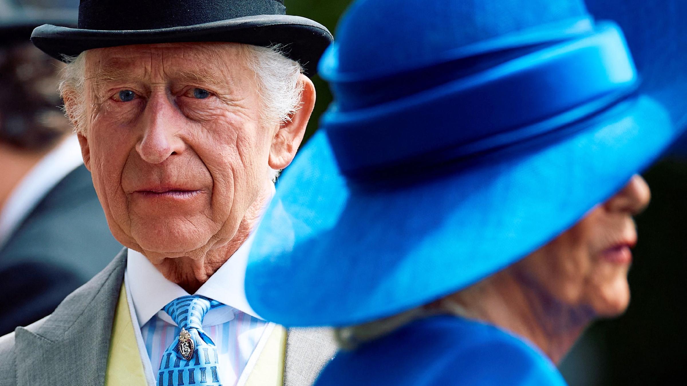 König Charles im Vordergrund Camilla mit blauem Hut