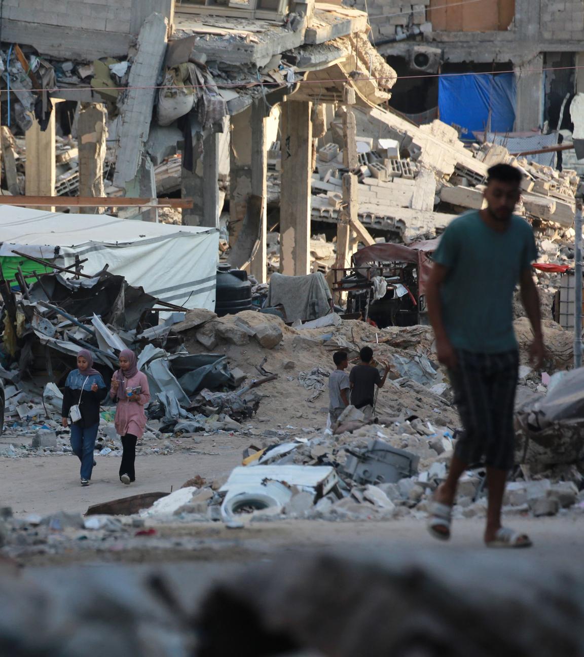 Menschen gehen an zerstörten Gebäuden in Chan Junis im südlichen Gazastreifen vorbei.