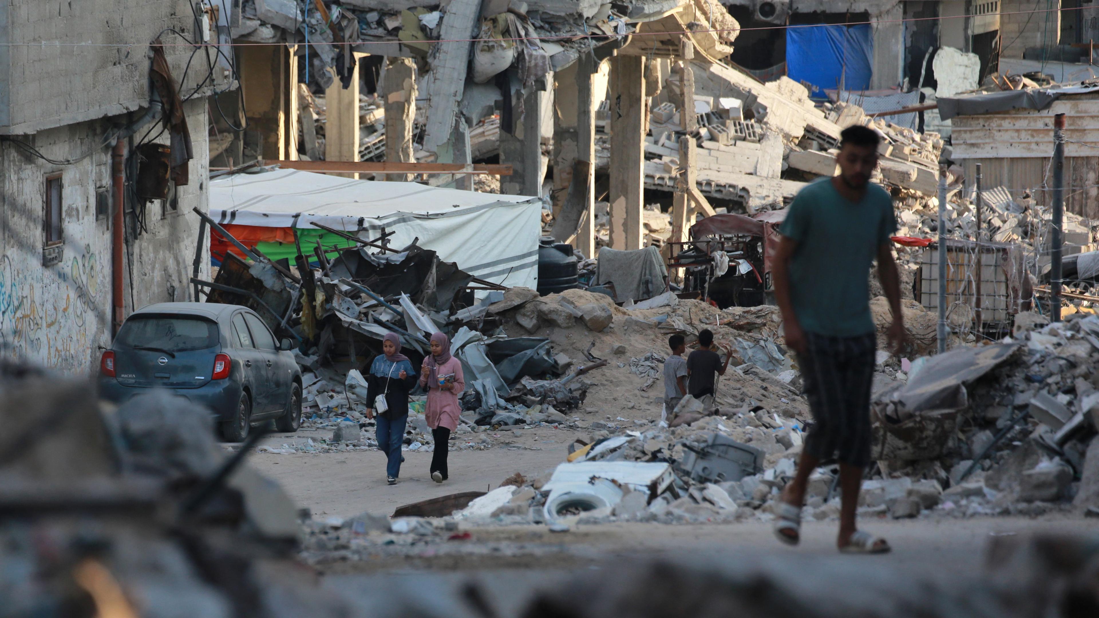 Menschen gehen an zerstörten Gebäuden in Chan Junis im südlichen Gazastreifen vorbei.