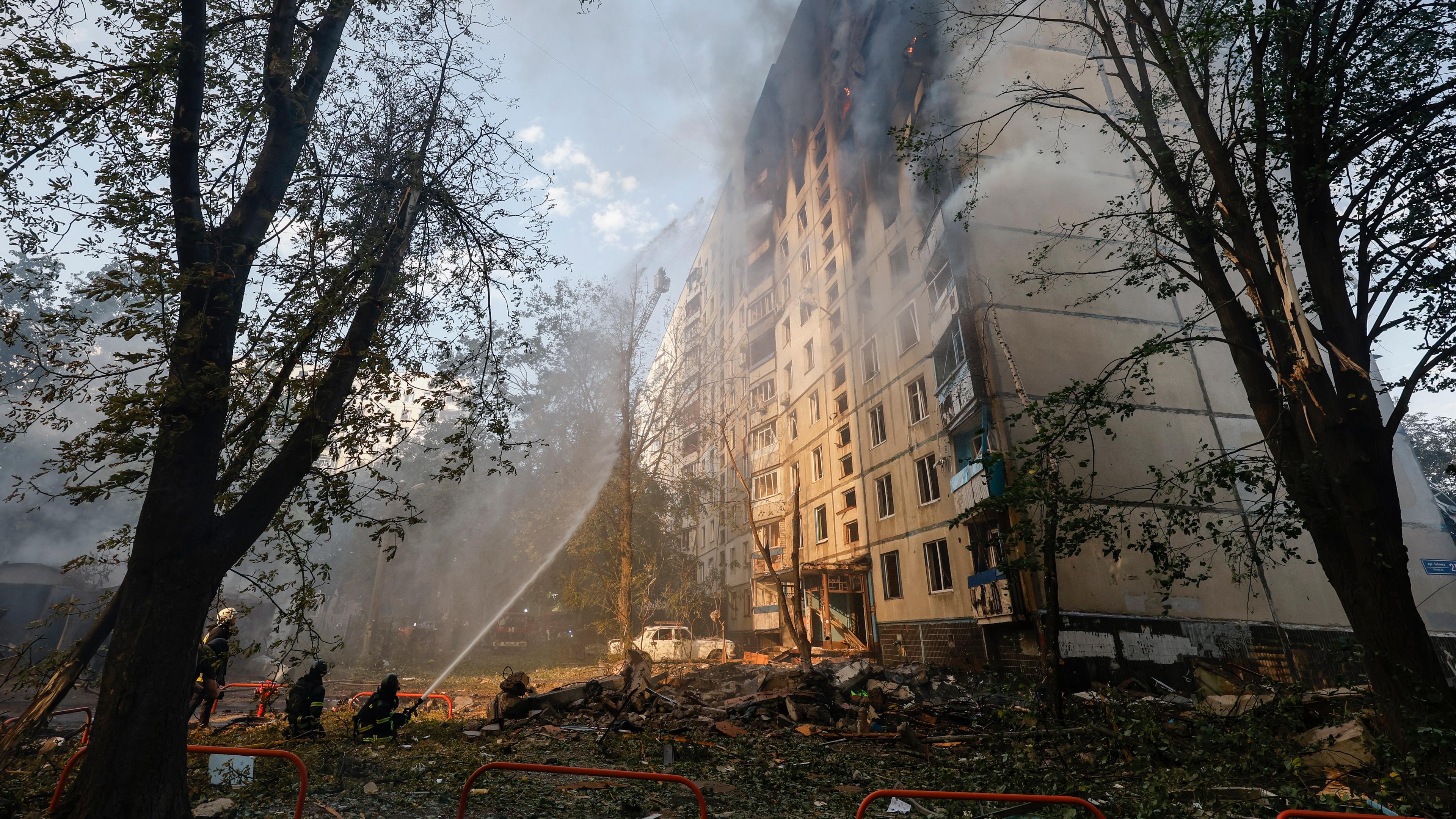 Menschen löschen den Brand eines Wohnhauses in Charkiw.