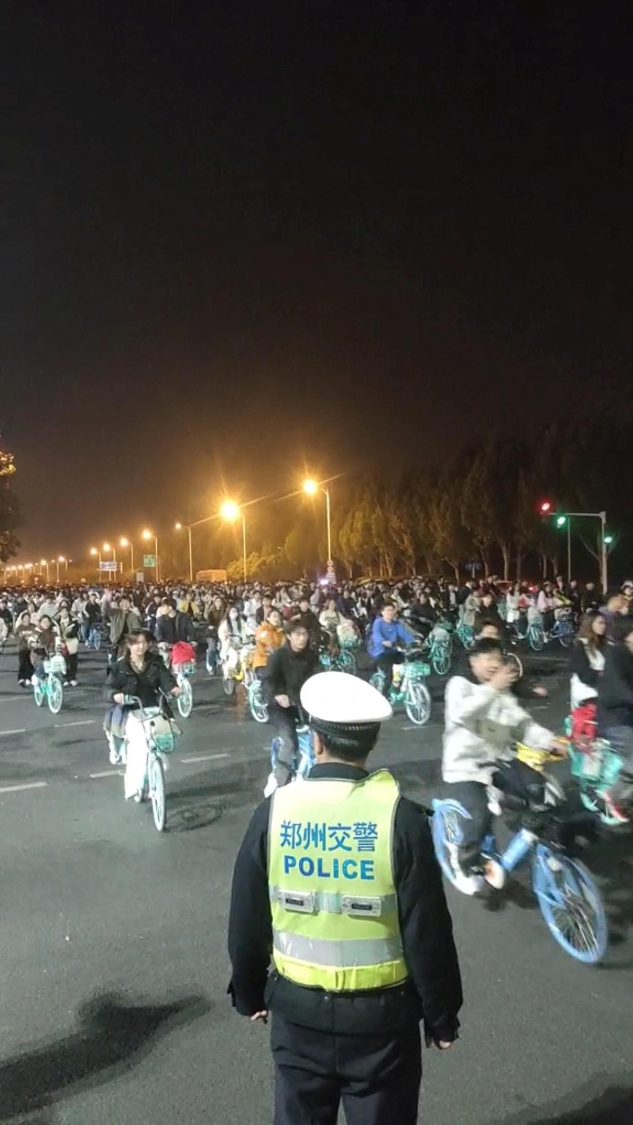 Zahlreiche Studenten fahren in China mit geliehenen Fahrrädern, neben ihnen ein Polizist. 