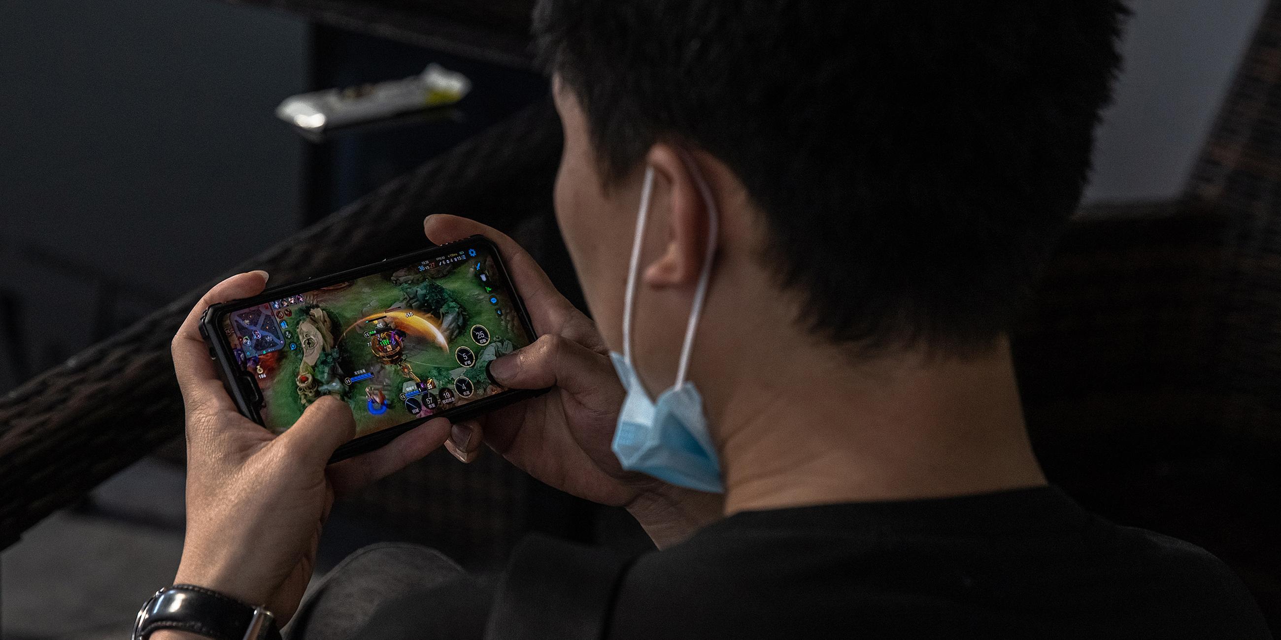 China, Peking: Ein junger Mann spielt "Honor of Kings" auf einem Smartphone.