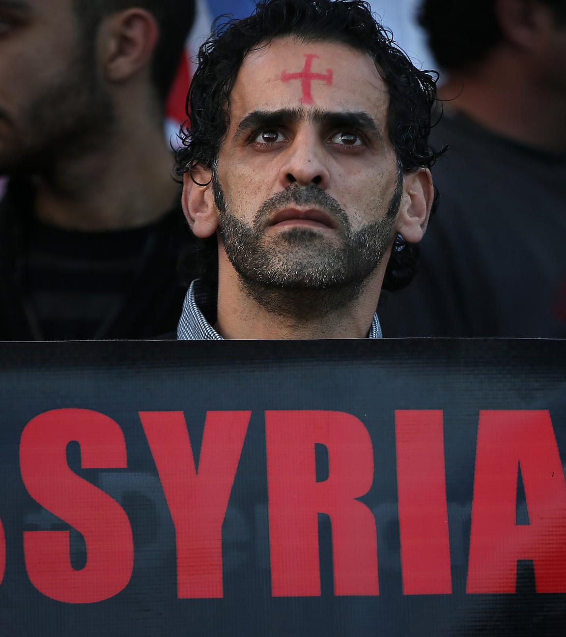 Ein assyrischer Mann mit einem Roten Kreuz auf der Stirn ein Banner, während er in der Innenstadt von Beirut gegen Christenverfolgung protestiert, aufgenommen am 28.02.2015 