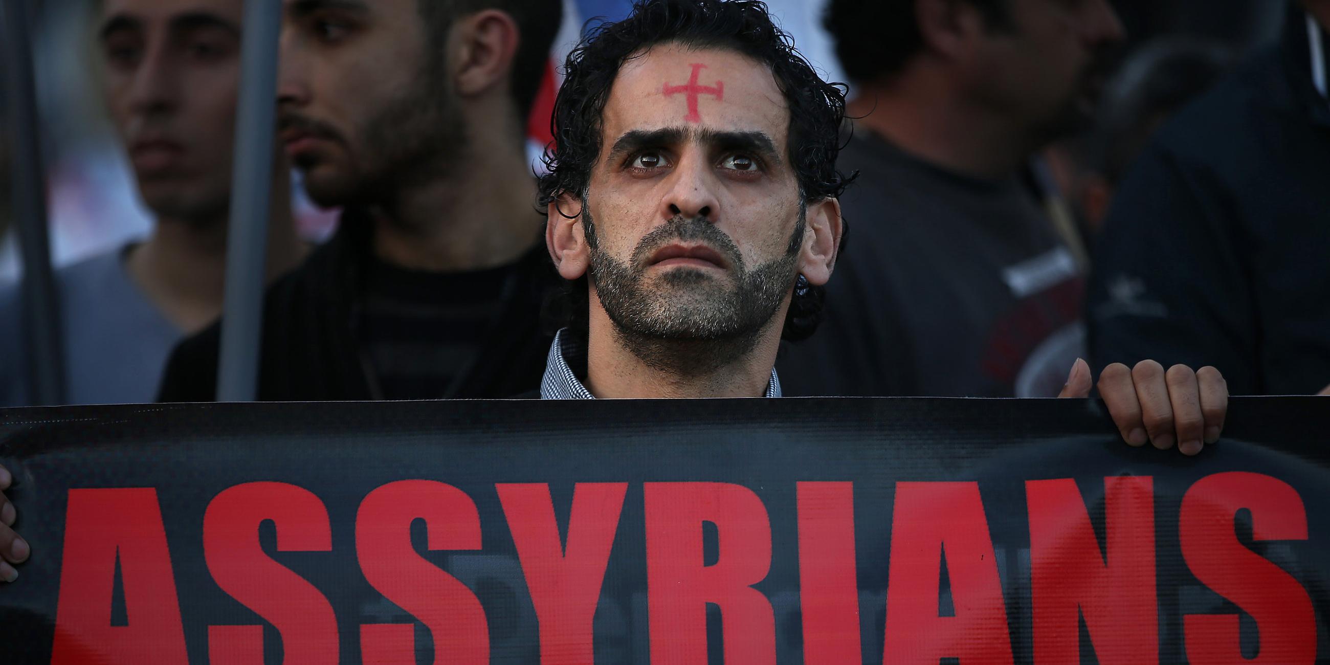 Ein assyrischer Mann mit einem Roten Kreuz auf der Stirn ein Banner, während er in der Innenstadt von Beirut gegen Christenverfolgung protestiert, aufgenommen am 28.02.2015 