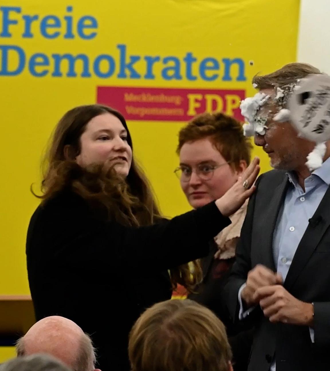 Der FDP-Vorsitzende Christian Lindner bekommt bei einem Wahlkampfauftritt in Greifswald von der Linke-Lokalpolitikerin Christiane Kiesow (l) Schaum ins Gesicht geworfen.