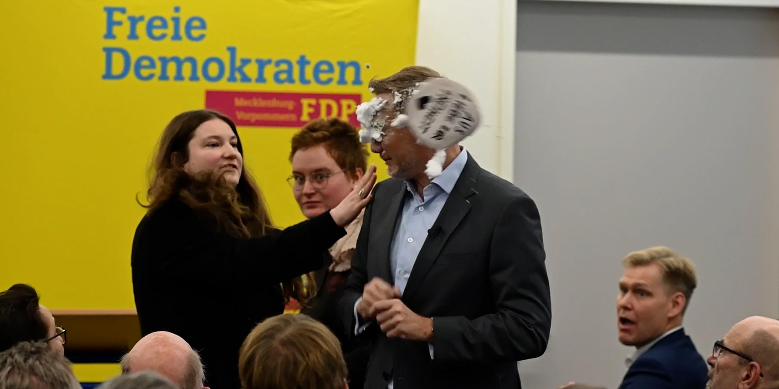 Der FDP-Vorsitzende Christian Lindner bekommt bei einem Wahlkampfauftritt in Greifswald von der Linke-Lokalpolitikerin Christiane Kiesow (l) Schaum ins Gesicht geworfen.