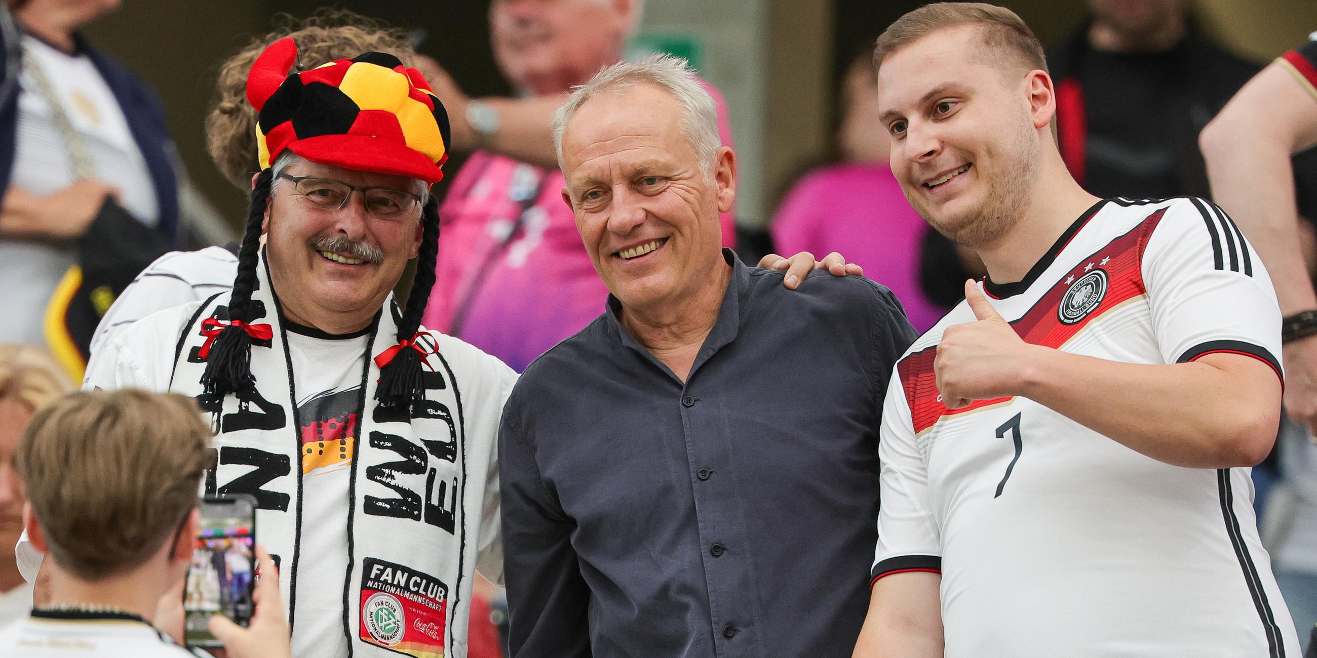 Fußball-EM 2024, Schweiz - Deutschland: Christian Streich, Ex-Trainer des SC Freiburg, lässt sich mit Fans auf der Tribüne fotografieren.