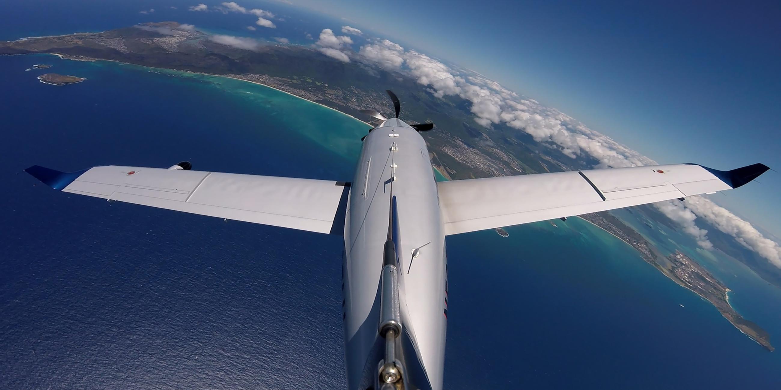 "Schatzinseln im Pazifik - Leben mit dem Ozean (1)": Eine Propellermaschine fliegt über das Meer und einen Landstrich mit Wolken.