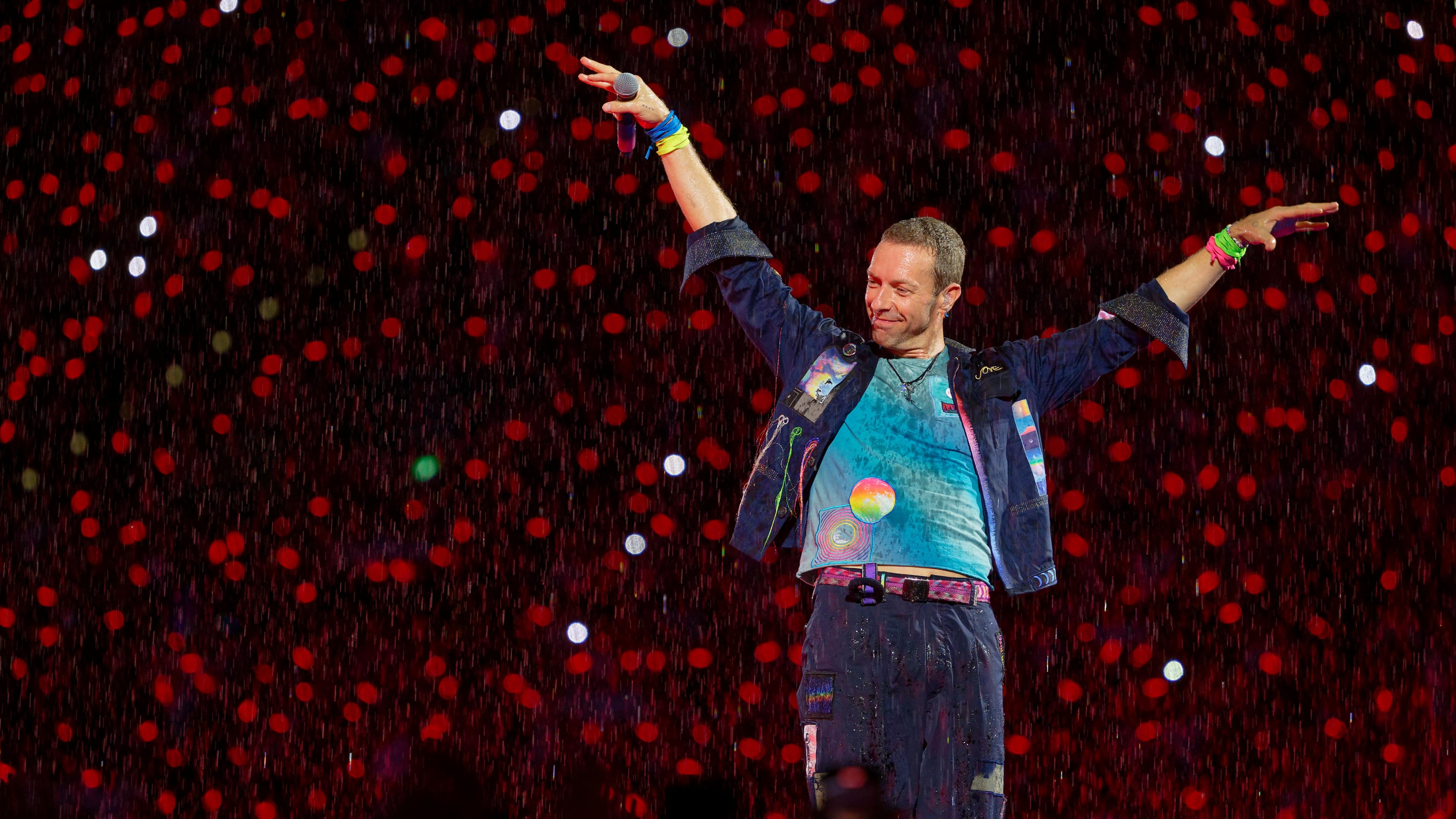 Chris Martin, Sänger der britischen Band Coldplay steht bei einem Konzert im Rahmen der "Music of the Spheres Tour 2024" bei strömendem Regen.