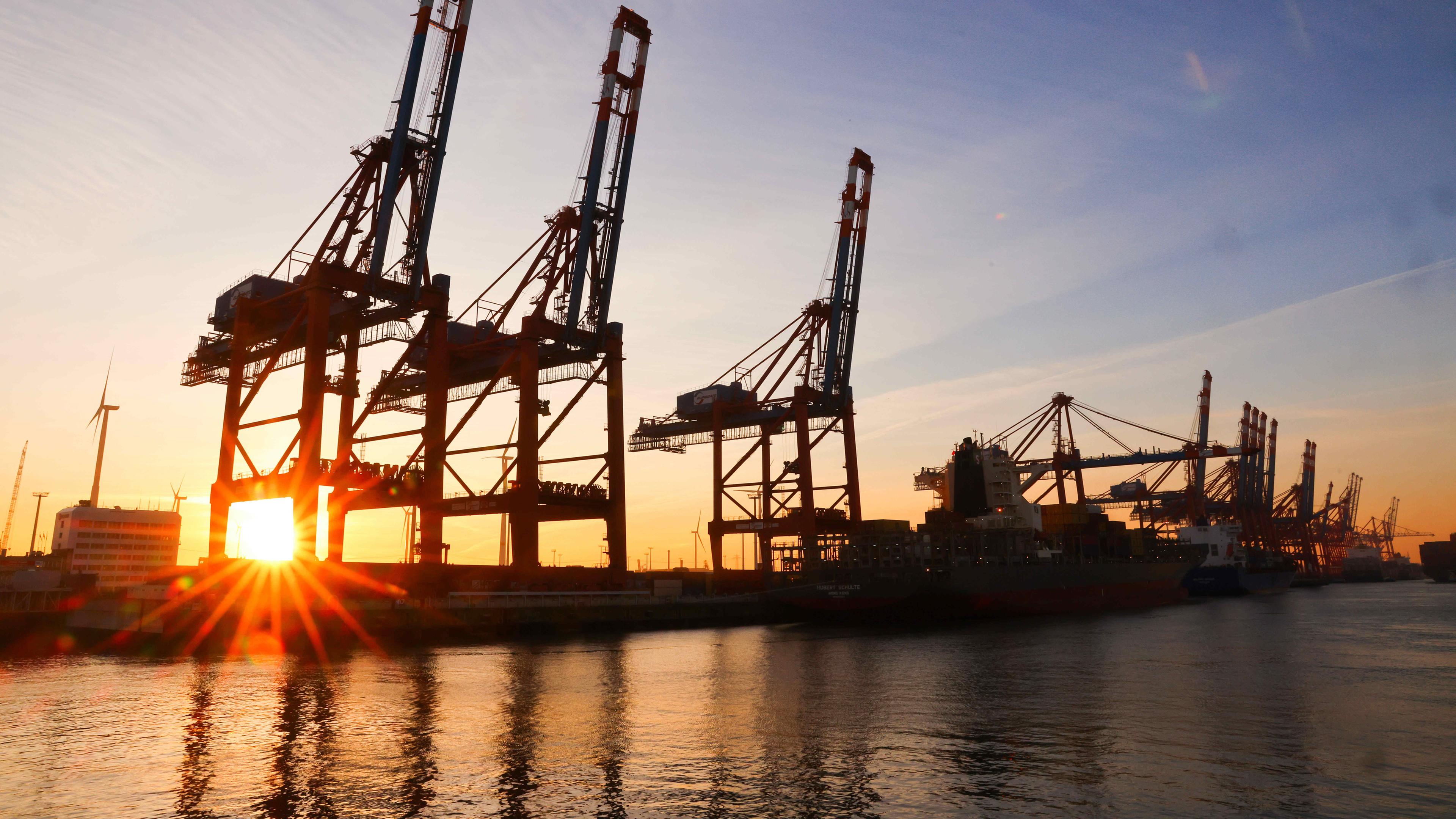 Die Sonne geht hinter Containerbrücken auf dem Terminal Eurogate im Waltershofer Hafen unter.