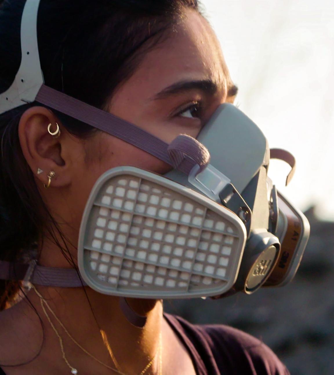 Porträtaufnahme der Journalistin Nelufar Hedayat: Sie hat die Haare zum Zopf gebunden trägt eine Atemschutzmaske und schaut zur Seite.