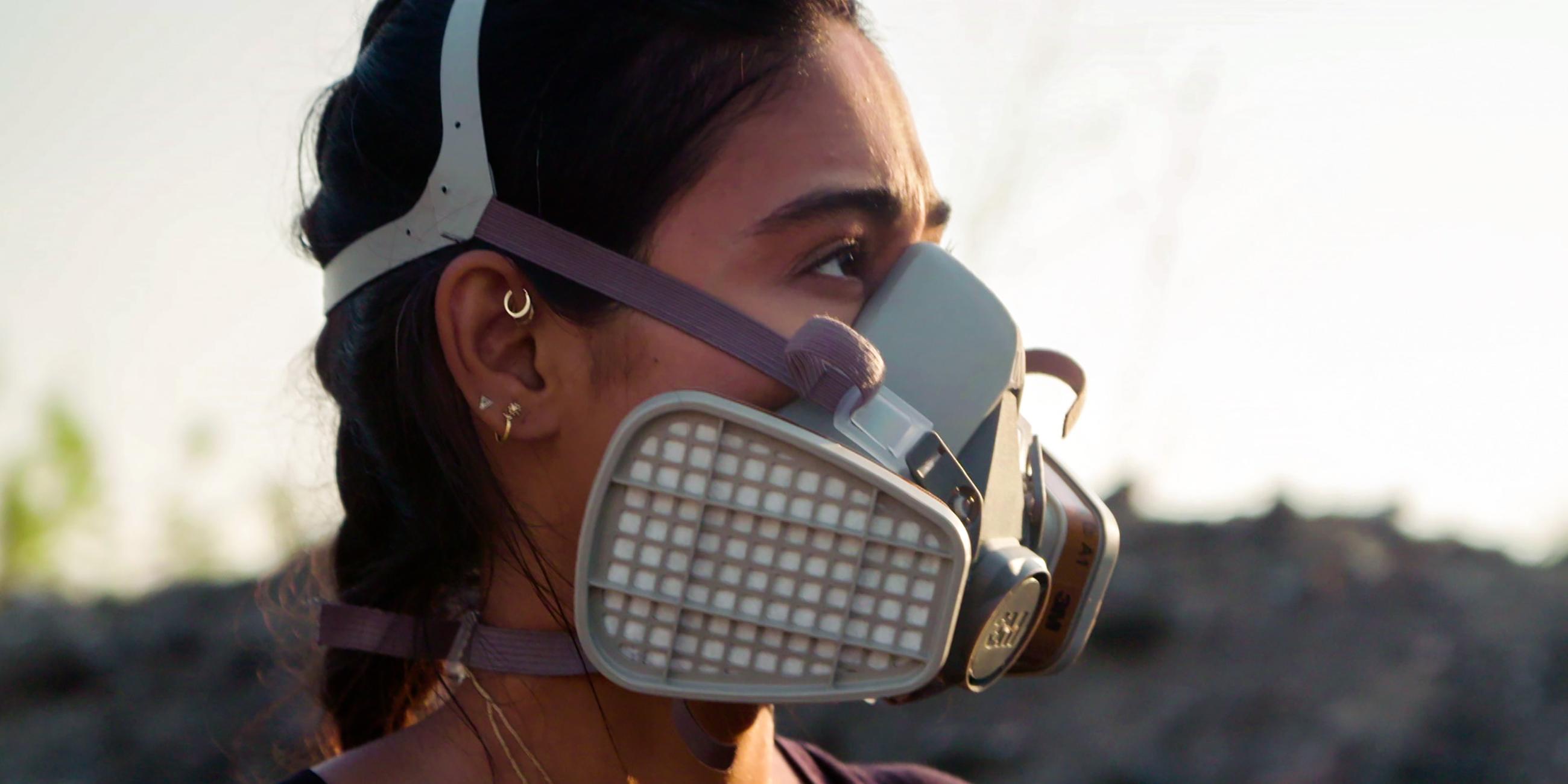 Porträtaufnahme der Journalistin Nelufar Hedayat: Sie hat die Haare zum Zopf gebunden trägt eine Atemschutzmaske und schaut zur Seite.