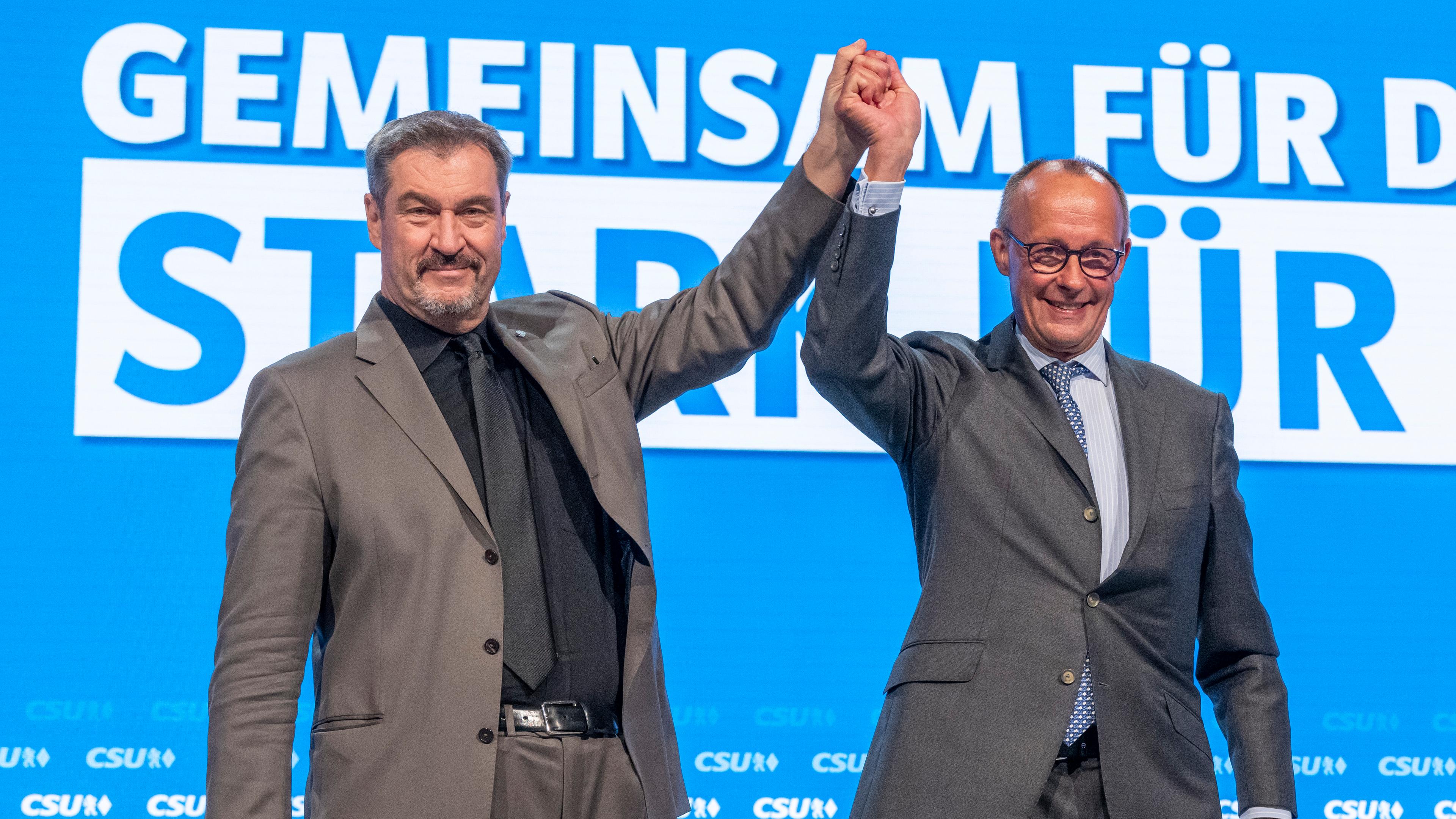 12.10.2024, Bayern, Augsburg: Friedrich Merz (r), CDU-Bundesvorsitzender und Unionsfraktionsvorsitzender, und Markus Söder, Vorsitzender der CSU, stehen auf dem Parteitag der CSU zusammen auf der Bühne.