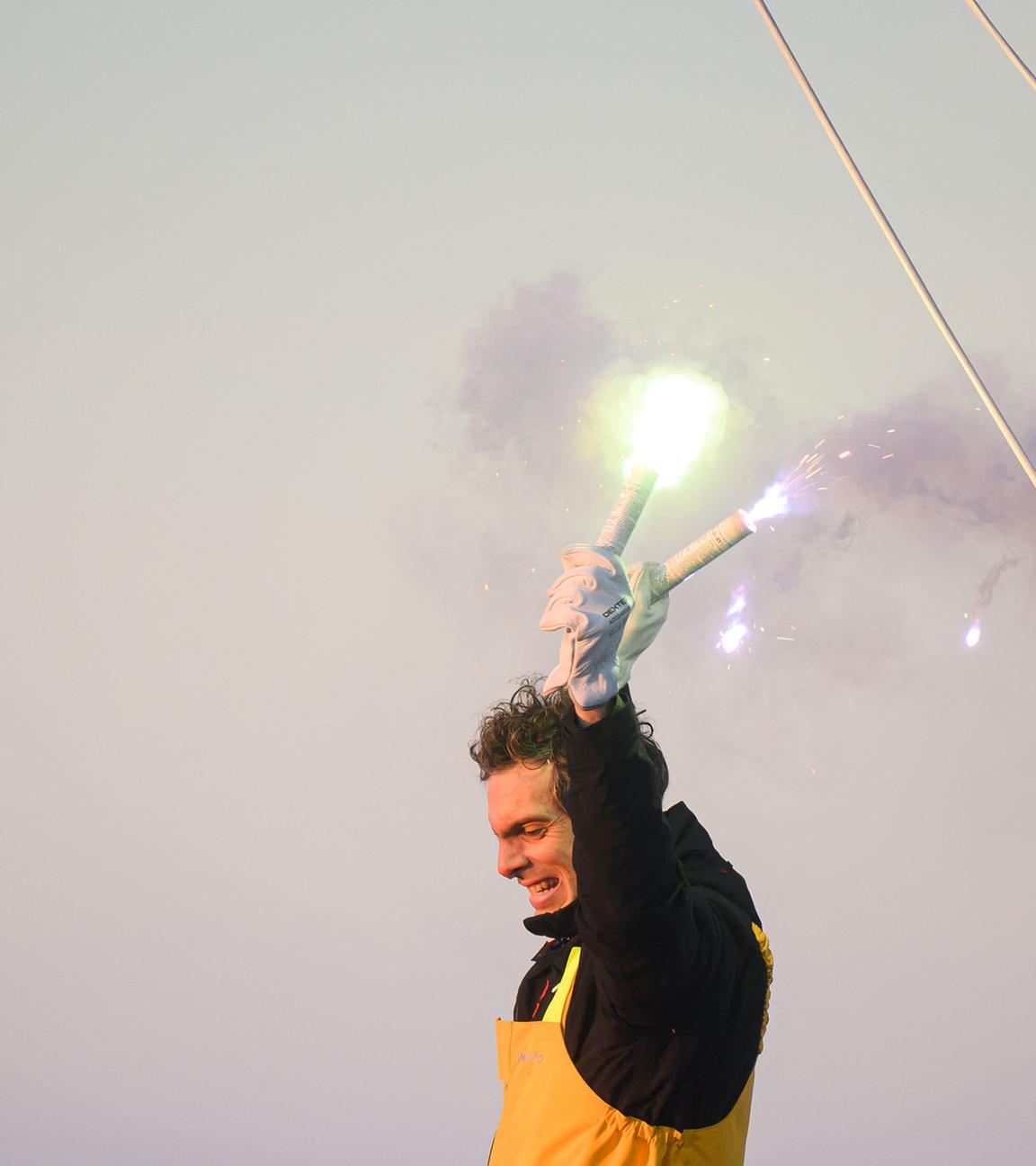 Vendee-Globe-Sieger Charlie Dalin hält im Ziel zwei Pyrotechnik-Fackeln in die Höhe.