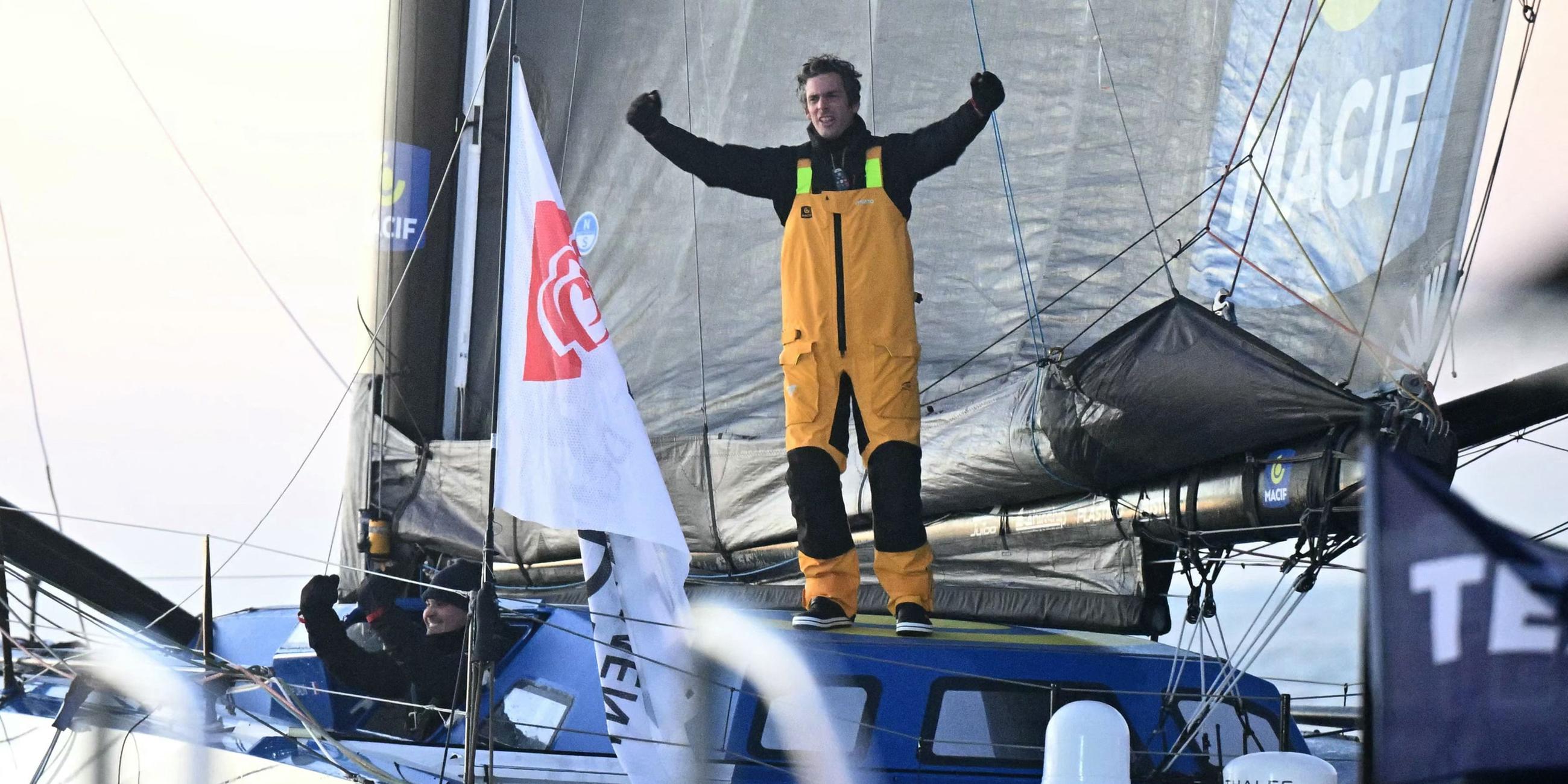 Vendee-Globe-Sieger Charlie Dalin im Ziel auf seinem Boot stehend.