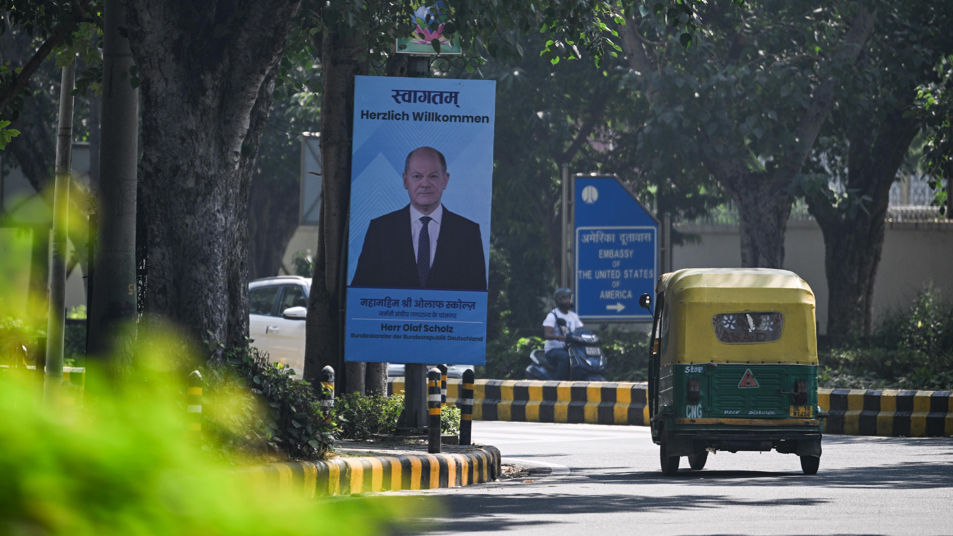 Ein Schild mit dem Bild von Bundeskanzler Scholz sowie dem Satz "Herzlich Willkommen" steht vor den deutsch-indischen Regierungskonsultationen an einer Straße in Neu-Delhi.