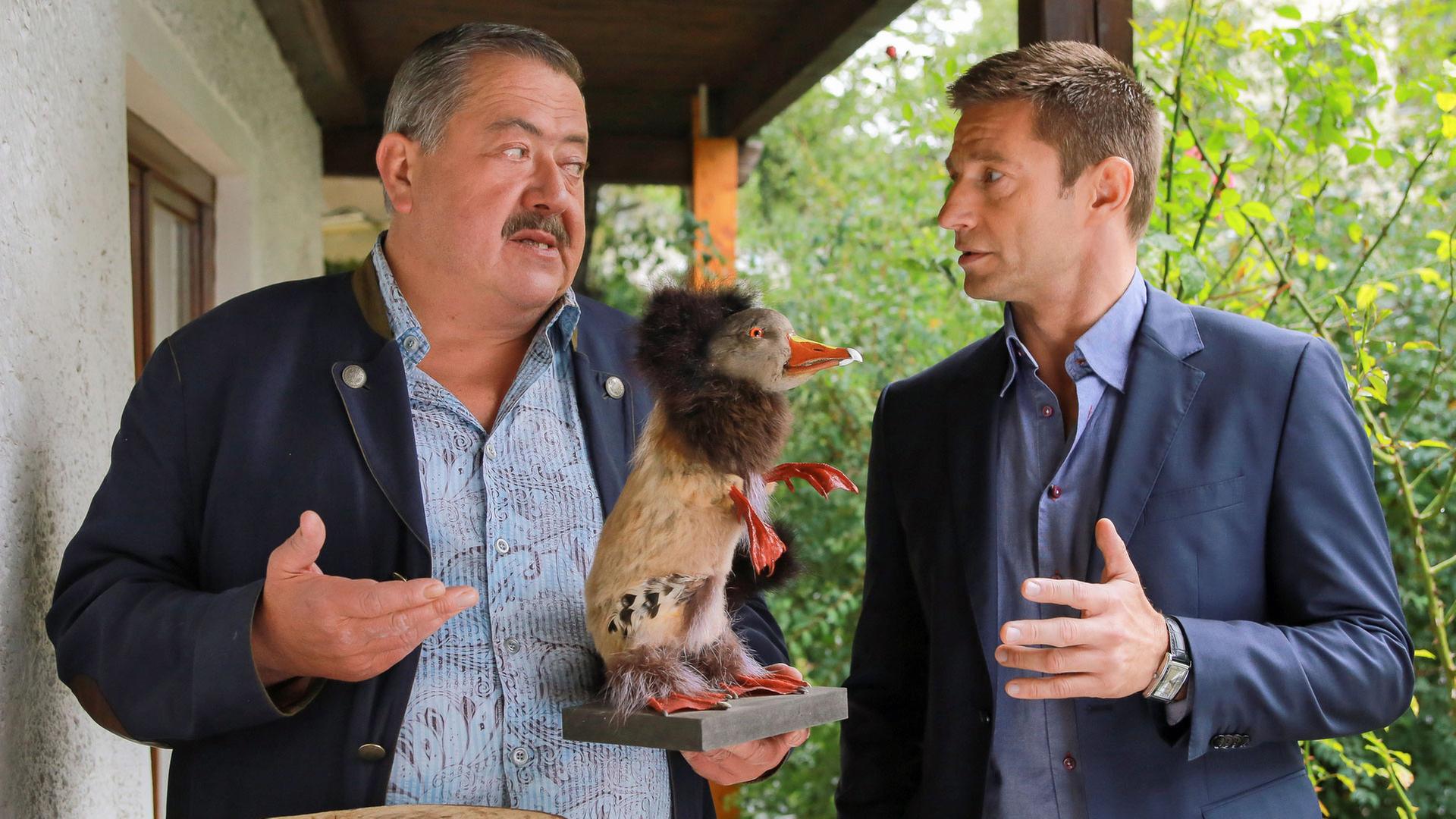 "Die Rosenheim-Cops - Der Fall der Felle": Vor einem Haus stehen die Kommissare Hofer (Joseph Hannesschläger) und Hansen (Igor Jeftic). Hofer hält einen Wolpertinger in der Hand.