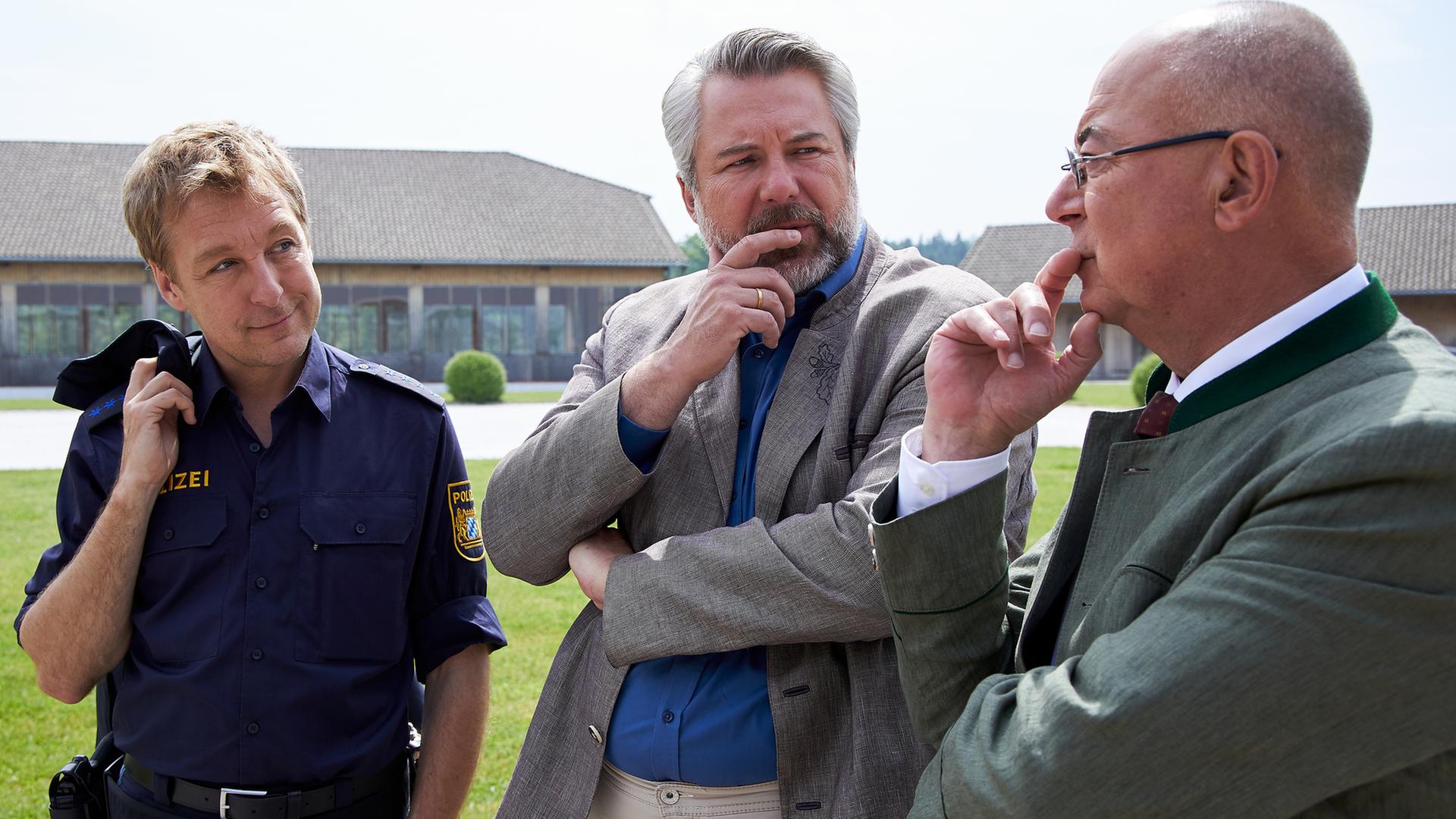 "Die Rosenheim-Cops - Der neue Mann": Polizeihauptmeister Mohr (Max Müller), Kommissar Stadler (Dieter Fischer) und Polizeidirektor Achtziger (Alexander Duda) stehen auf der Wiese vor dem Reiterhof und machen nachdenkliche Gesichter.