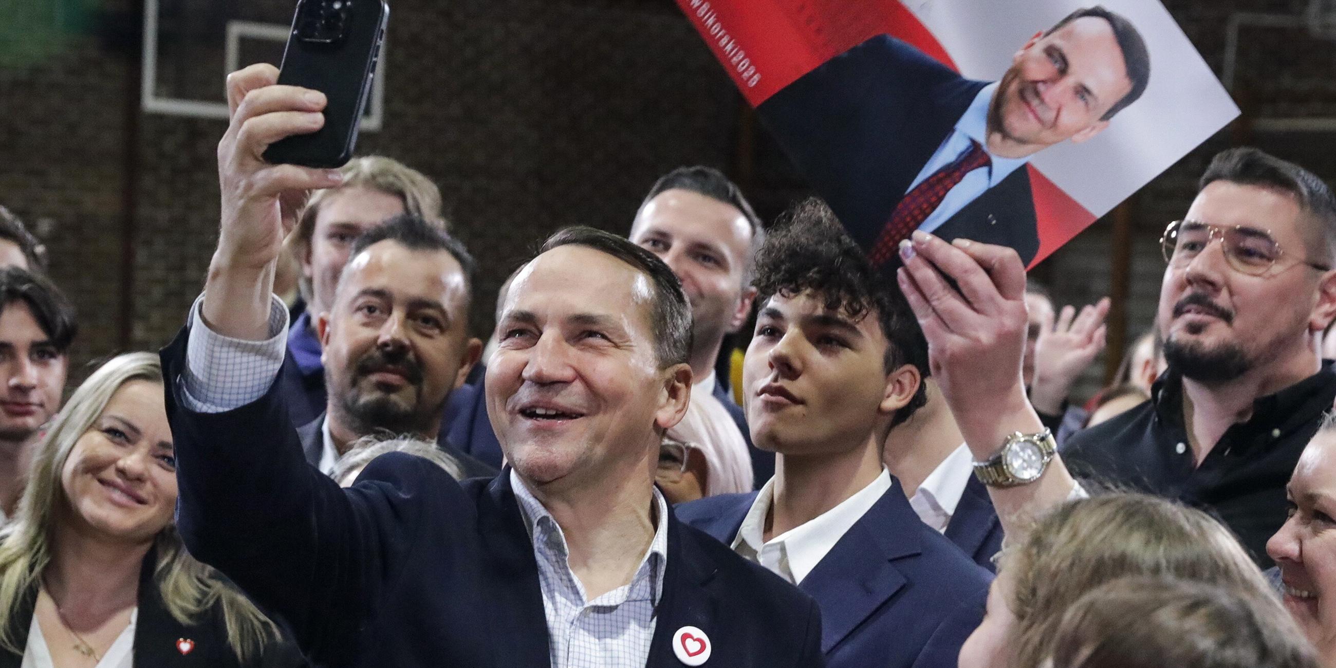 Der polnische Außenminister Radoslaw Sikorski (Mitte) von der Regierungspartei Bürgerplattform posiert für ein Selfie während seines Treffens mit Anwohnern in Pruszkow, Zentralpolen, 17. 11. 2024.