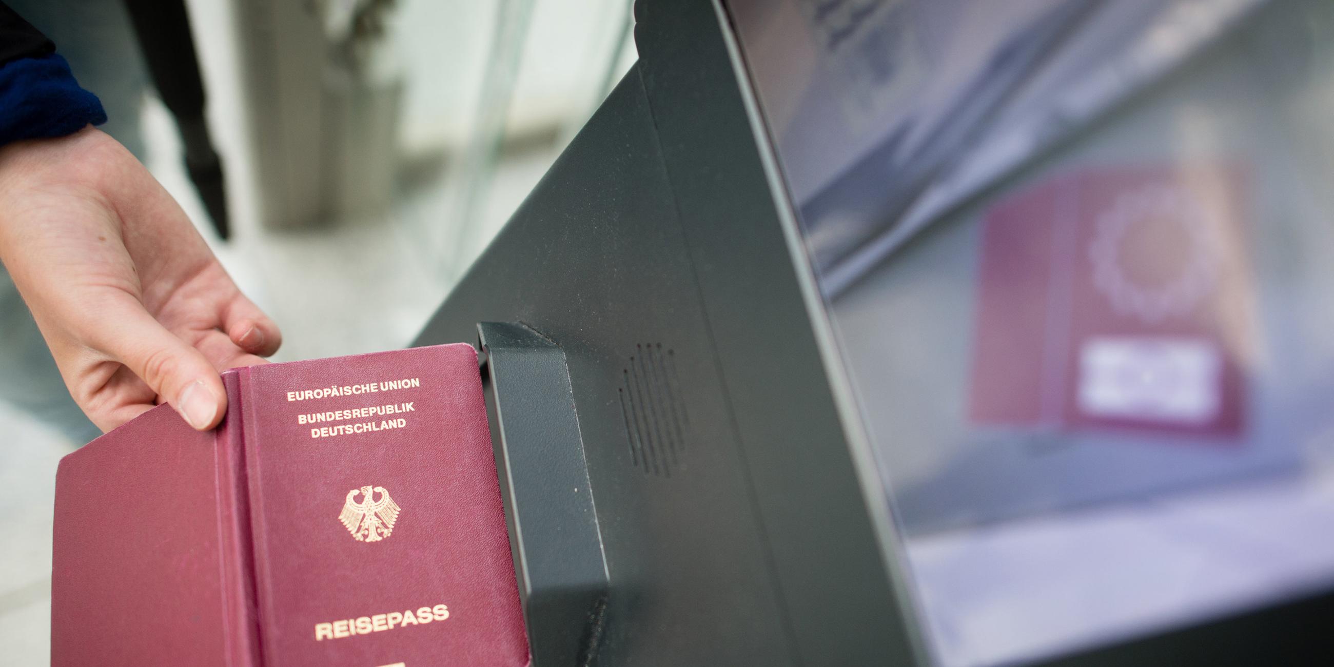 Eine Person am Flughafen hält ihren deutschen Reisepass an ein Gerät.