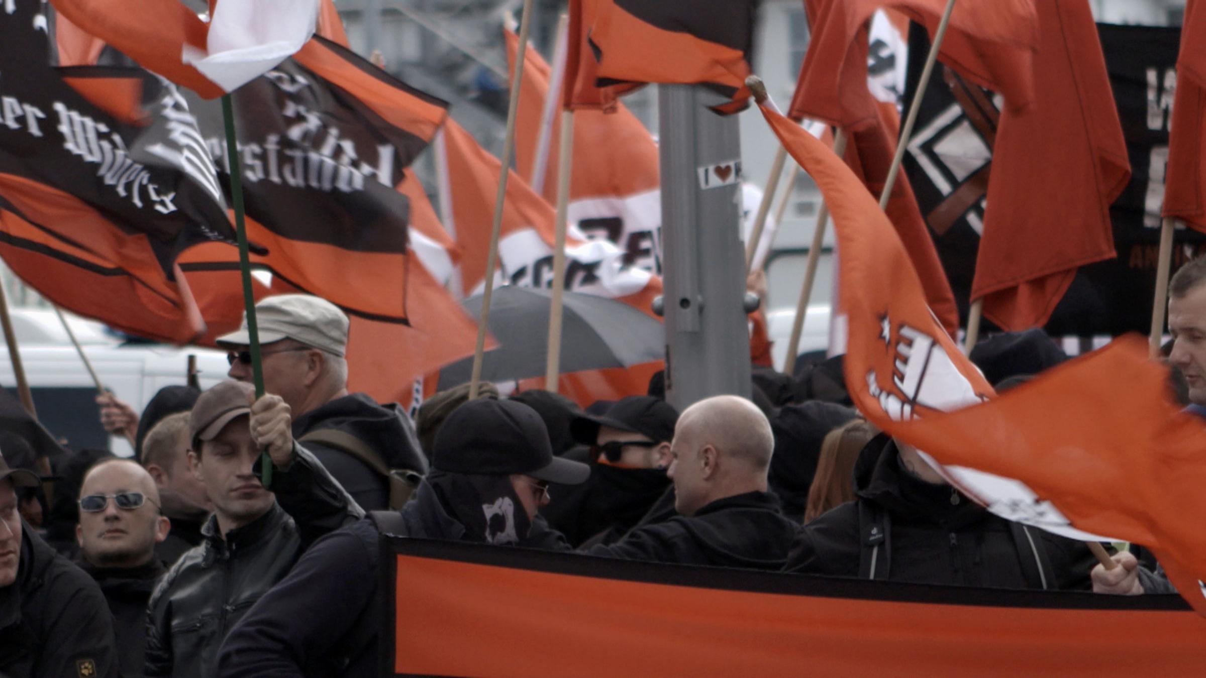 Rechte Demonstration zum 1. Mai in Halle. Viele schwarz gekleidete Menschen halten Fahnen mit Parolen hoch.