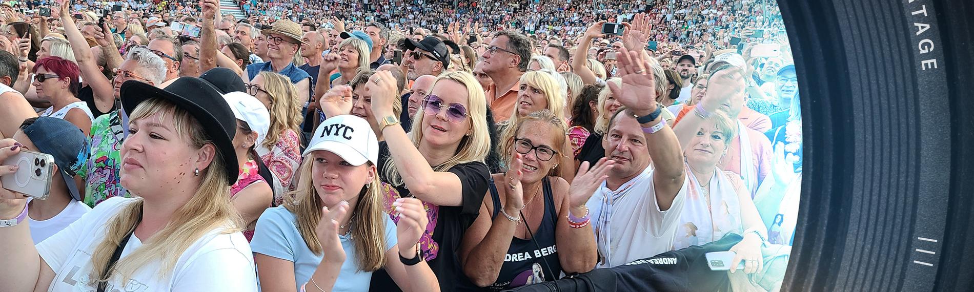 Blick auf Schlagerfans im Stadion. Im Vordergrund, an der Absperrung, stehen die leidenschaftlichen Schlagerfans Tanja Convent-Lorenz und ihre Tochter Leia.