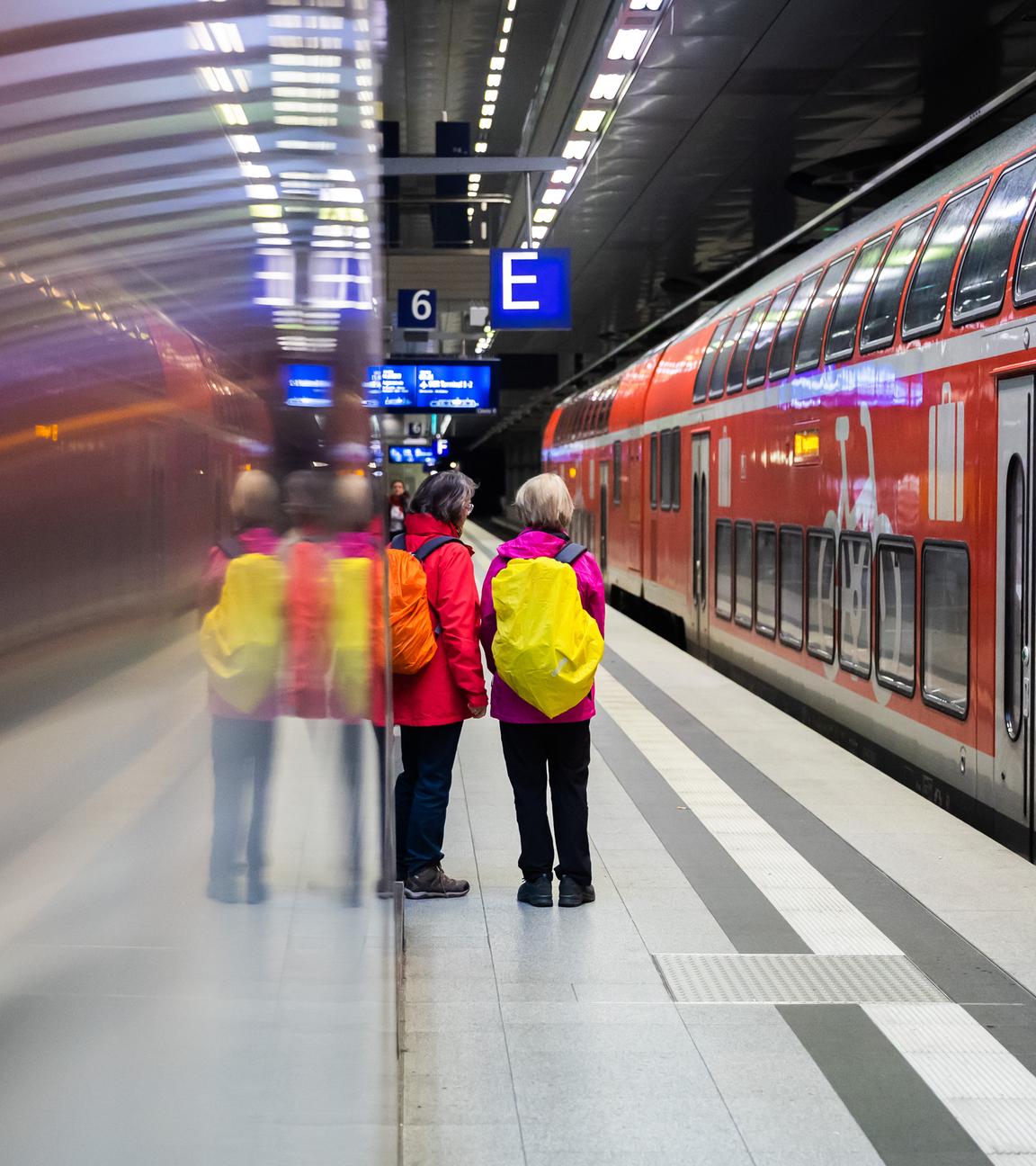 Fahrgäste stehen am Berliner Hauptbahnhof neben einem Regionalexpress am Bahnsteig.