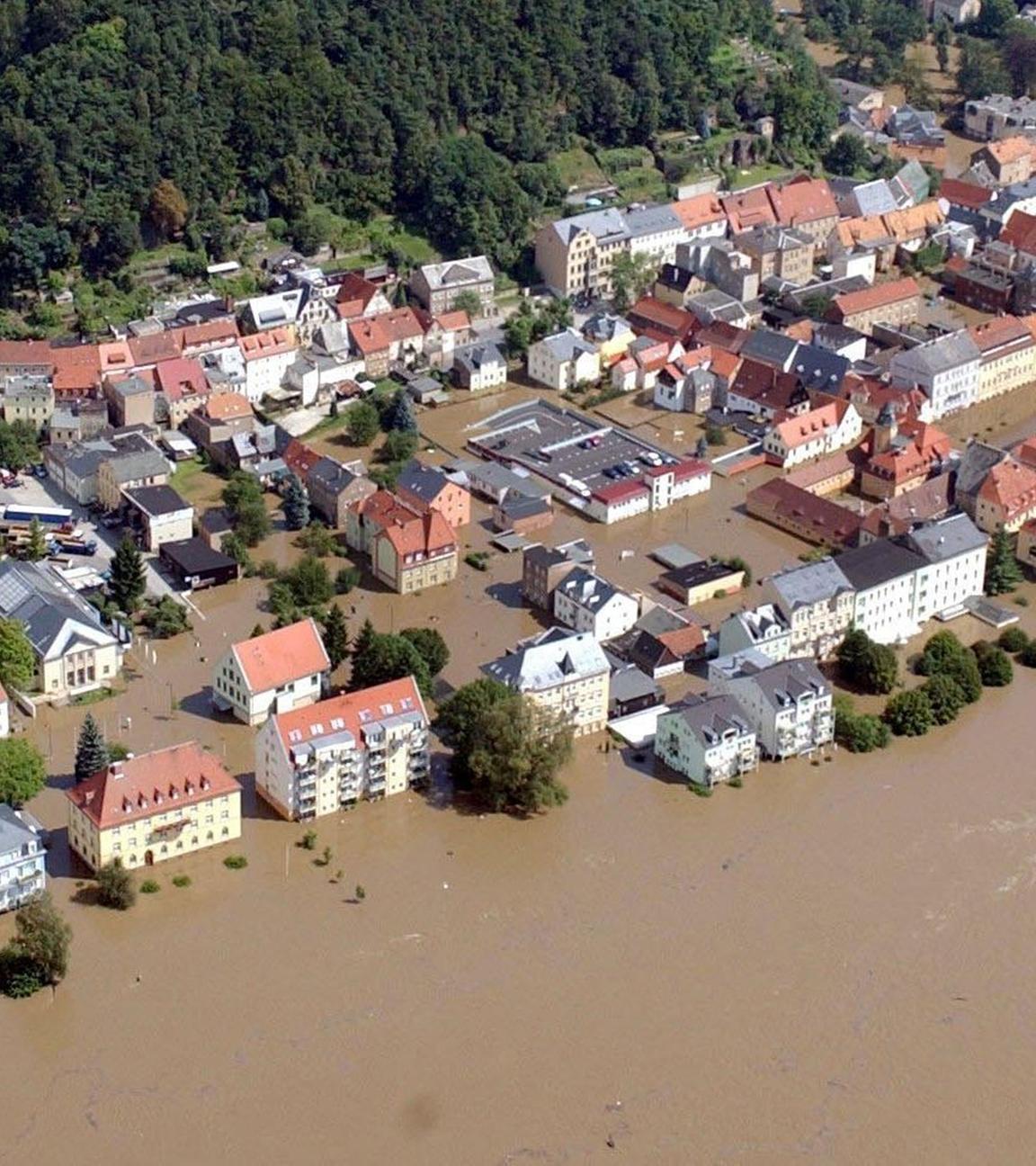 "Die 2000er - Jahrzehnt der Spaltung: 2002-2004 - Naturgewalt und Nipplegate" Vogelperspektive über überfluteten Gebäuden einer Stadt.