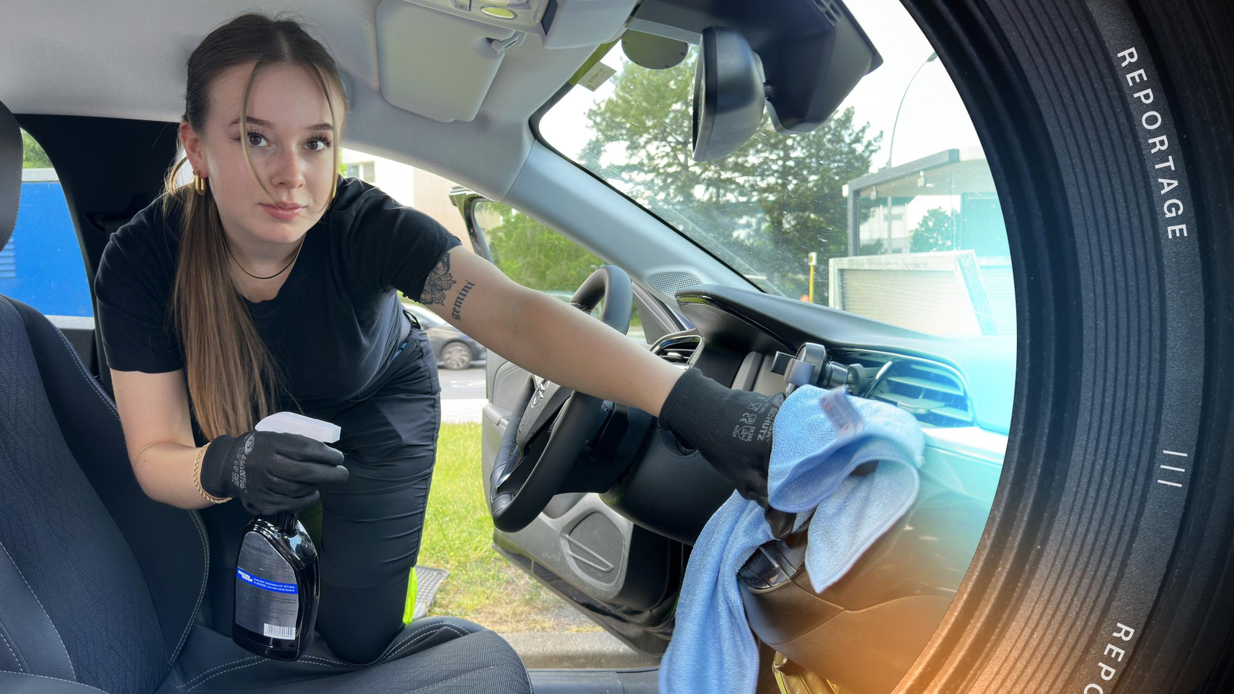 Jolina (22) kniet im Auto auf dem Fahrersitz und schaut in die Kamera. In ihren behandschuhten Händen hält sie ein Putztuch und eine Flasche mit Reinigungsmittel.