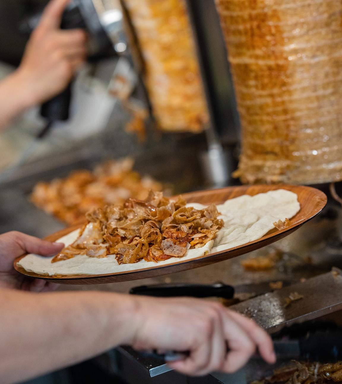  Ein Mitarbeiter einer Dönerbude legt Fleisch auf einen Döner.