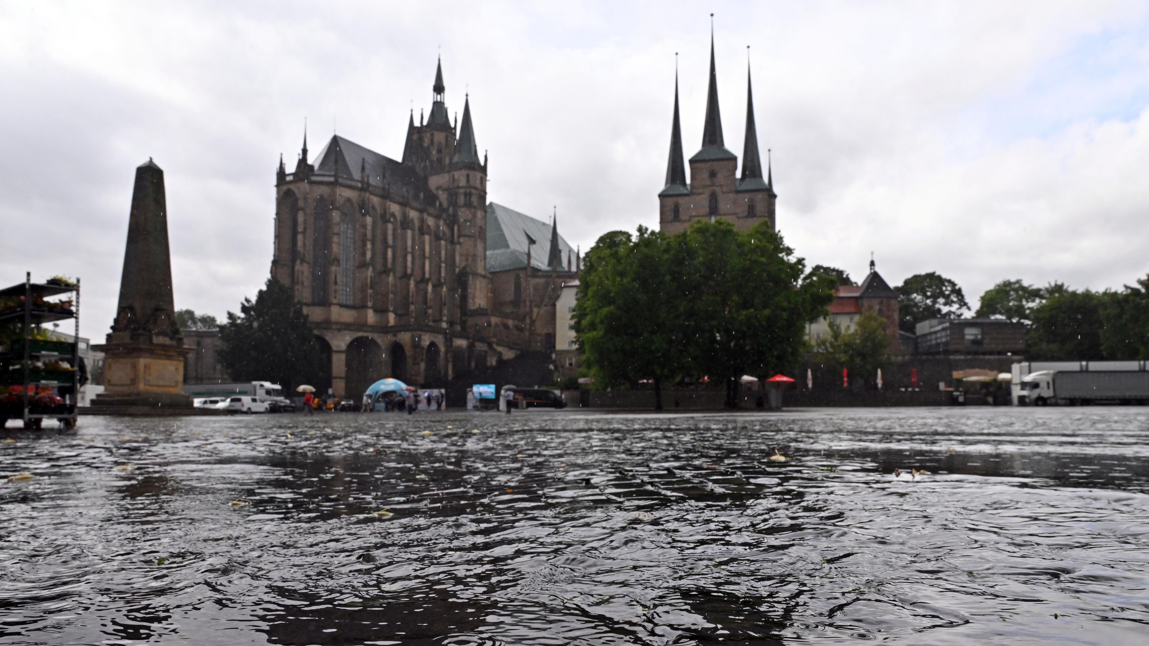 Wasser fließt bei starkem Regen über den Domplatz vor dem Mariendom und der Severikirche.