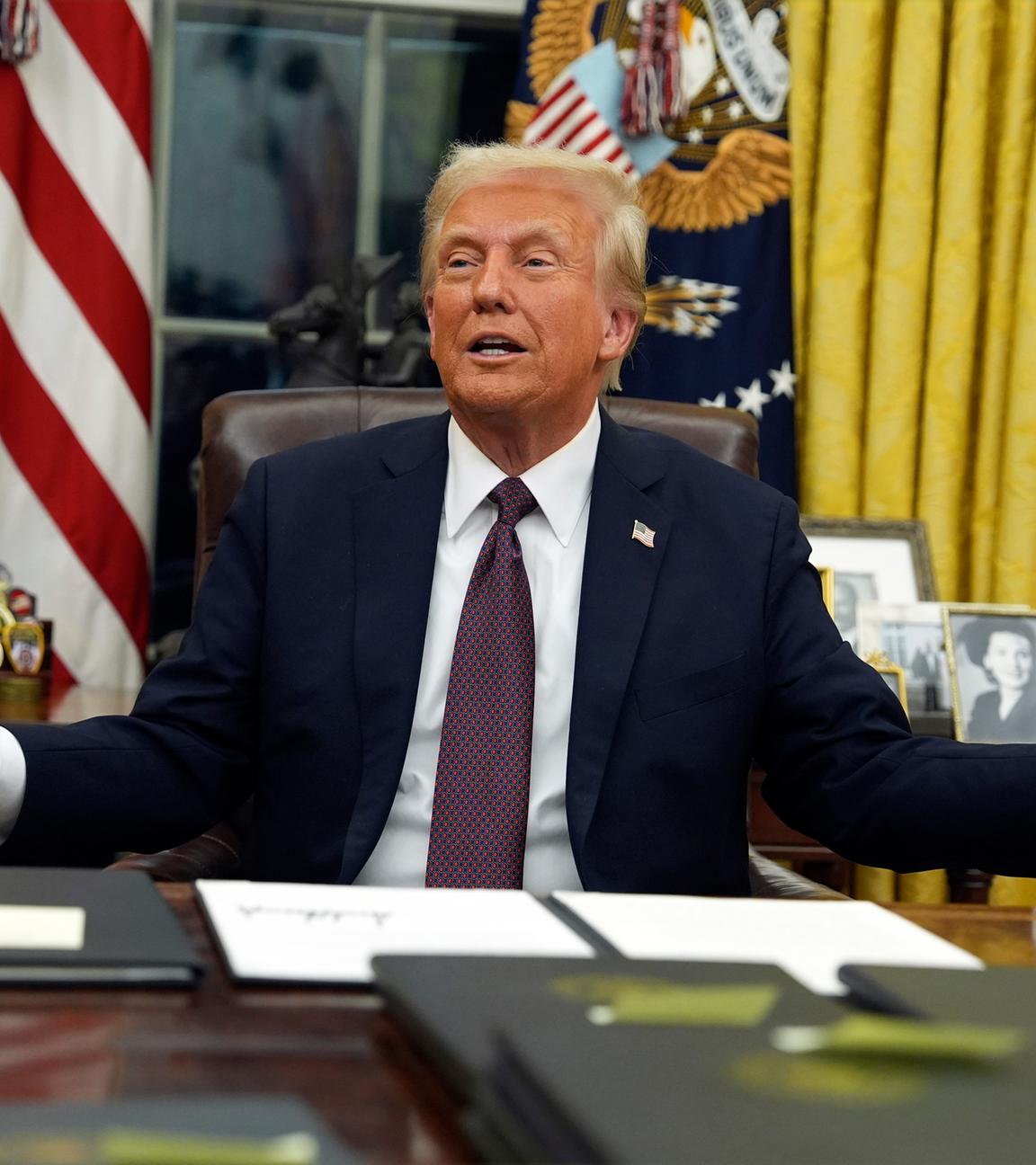 Donald Trump sitzt im Oval Office und hält einen Brief in der Hand.