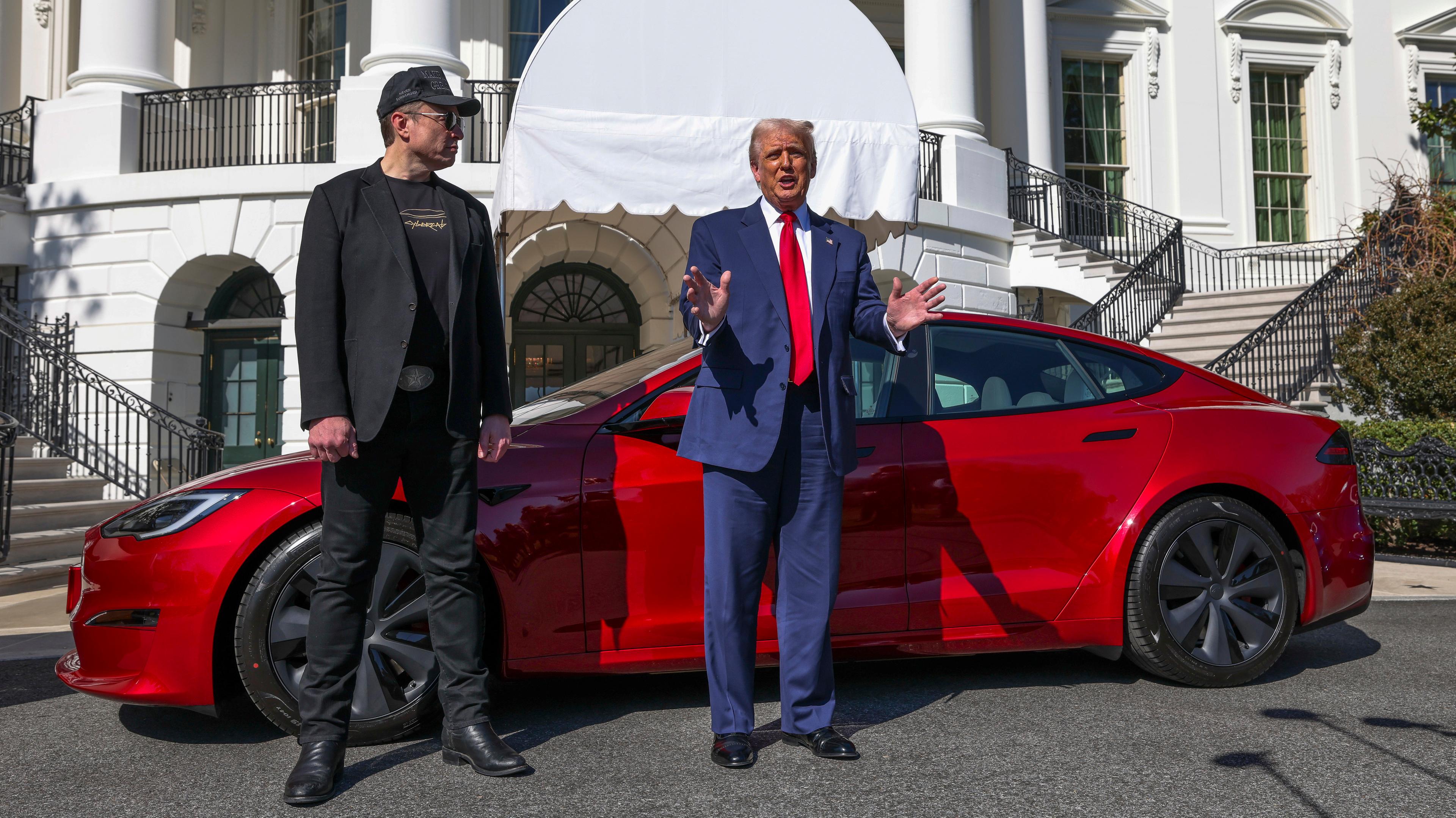 US-Präsident Donald Trump (r) und Tesla-CEO Elon Musk sprechen zu Reportern vor einem roten Tesla Model S auf dem Südrasen des Weißen Hauses