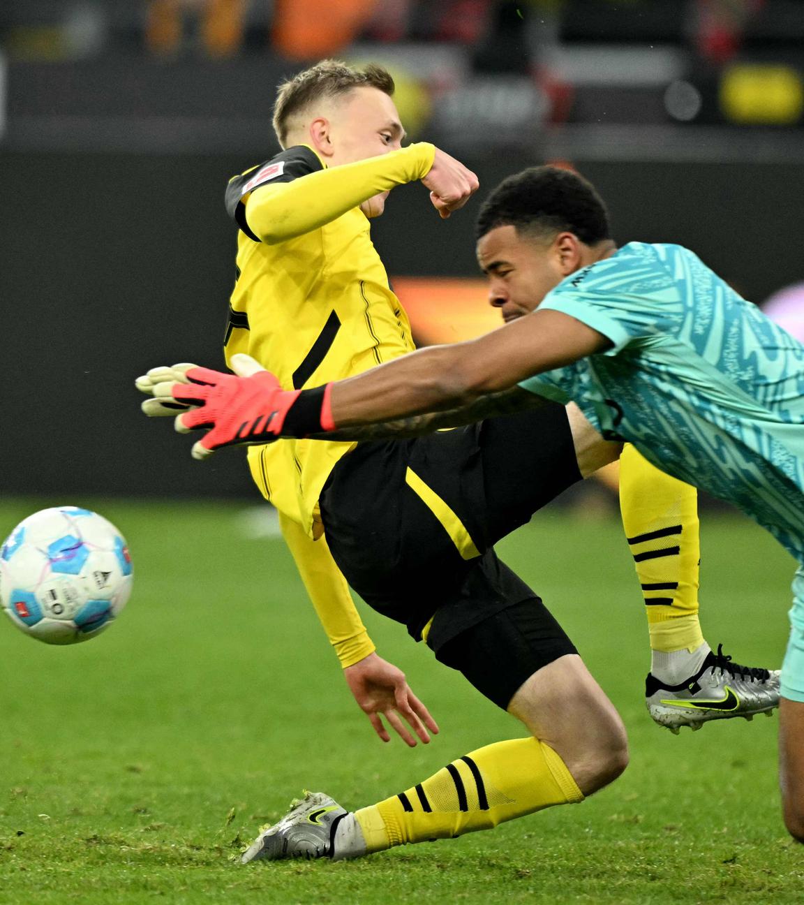 Dortmunds Stürmer (Nr. 14) Maximilian Beier (L) und Freiburgs Torhüter (Nr. 01) Noah Atubolu kämpfen um den Ball.