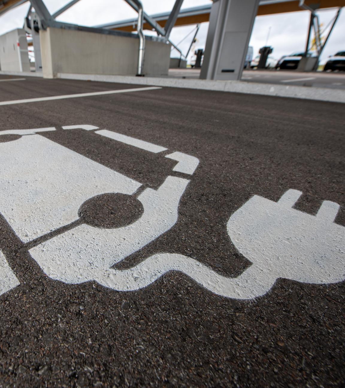 Eine Reihe von Parkplätzen für E-Autos, welche jeweils piktografisch mit einem Auto mit Stromstecker gekennzeichnet sind.