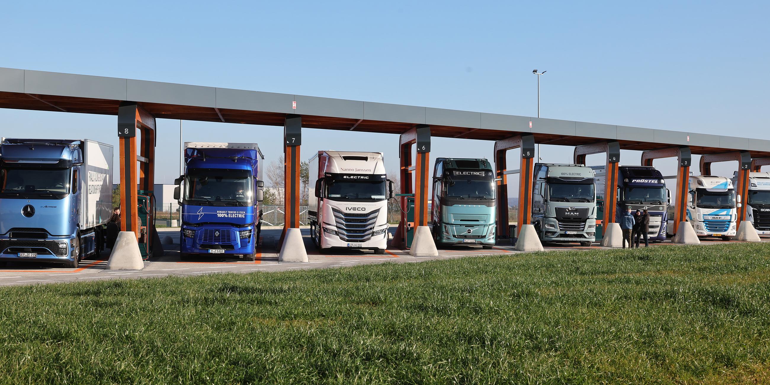 Lkw mit Elektroantrieb stehen in einer Ladebox eines Ladeparks für E-Lastwagen am Hermsdorfer Kreuz