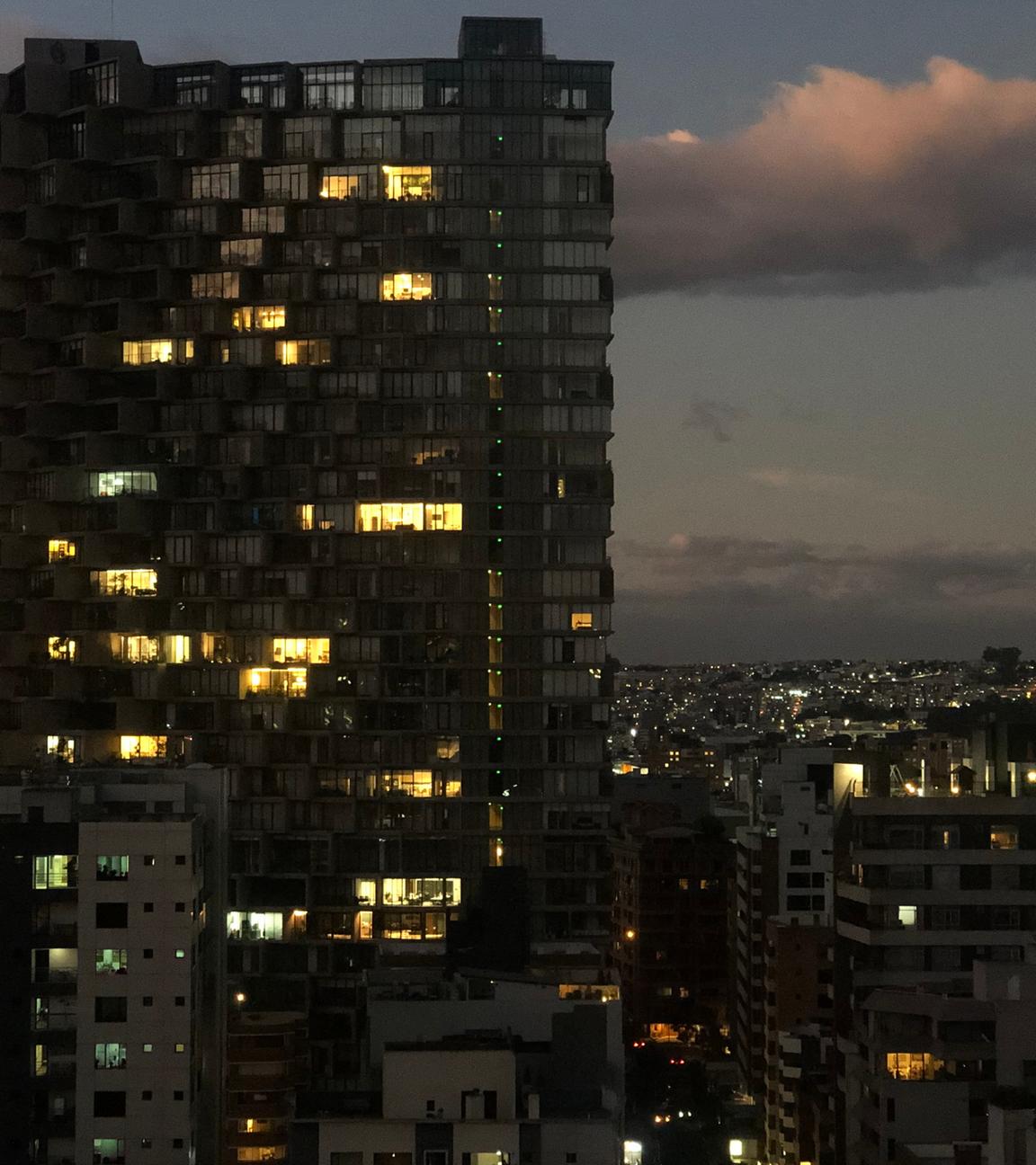 Ein Hochhaus in Quito, Ecuador in der Nacht. Nur wenige Fenster sind beleuchtet.