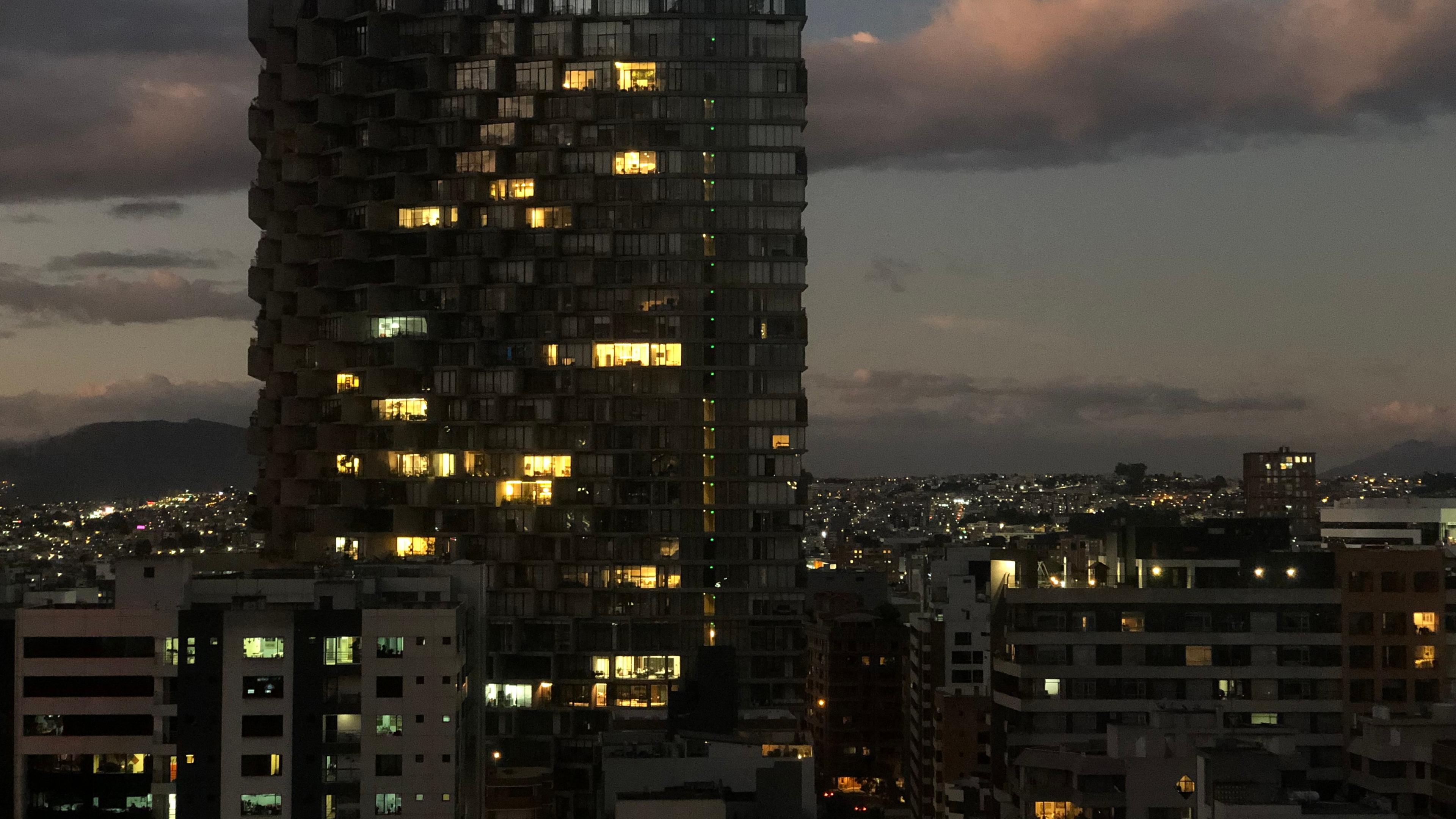 Ein Hochhaus in Quito, Ecuador in der Nacht. Nur wenige Fenster sind beleuchtet.