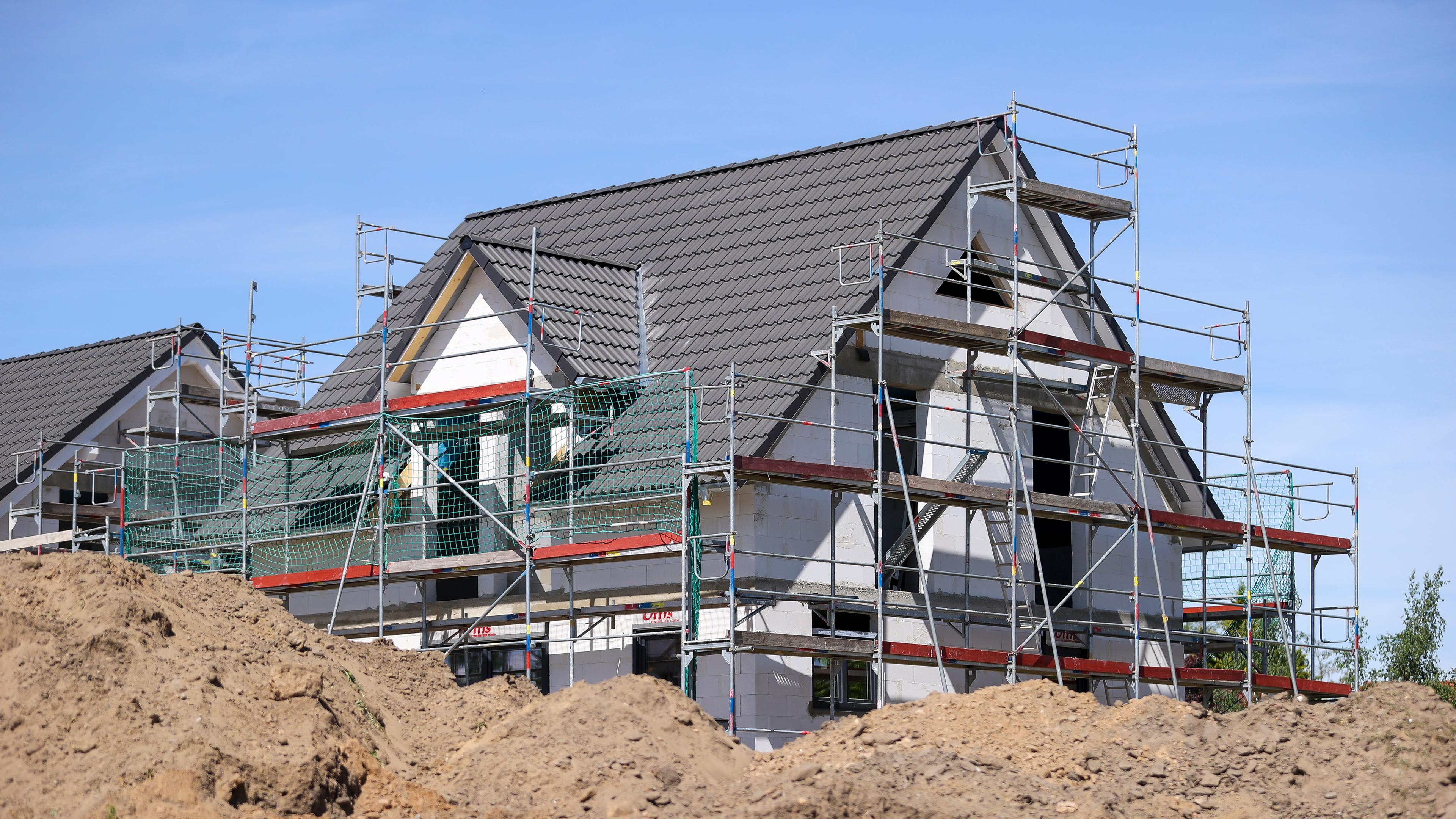 Construction of a single-family home with scaffolding and a pile of earth in front of it