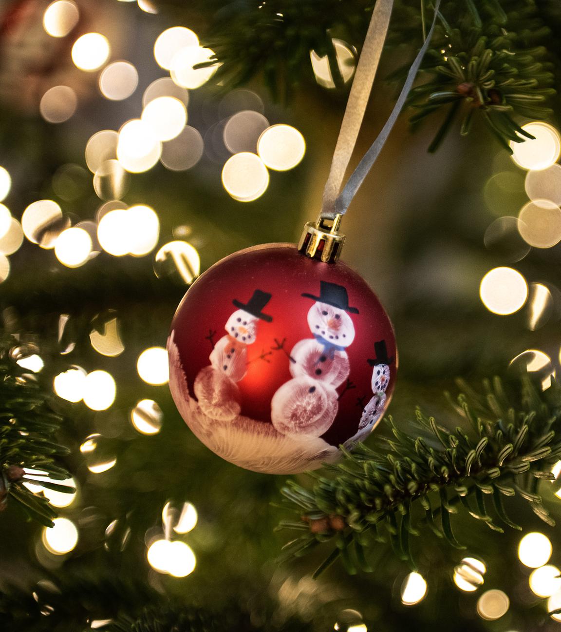 Niedersachsen, Göttingen: Eine Weihnachtskugel hängt an einem Weihnachtsbaum mit einer Lichterkette.