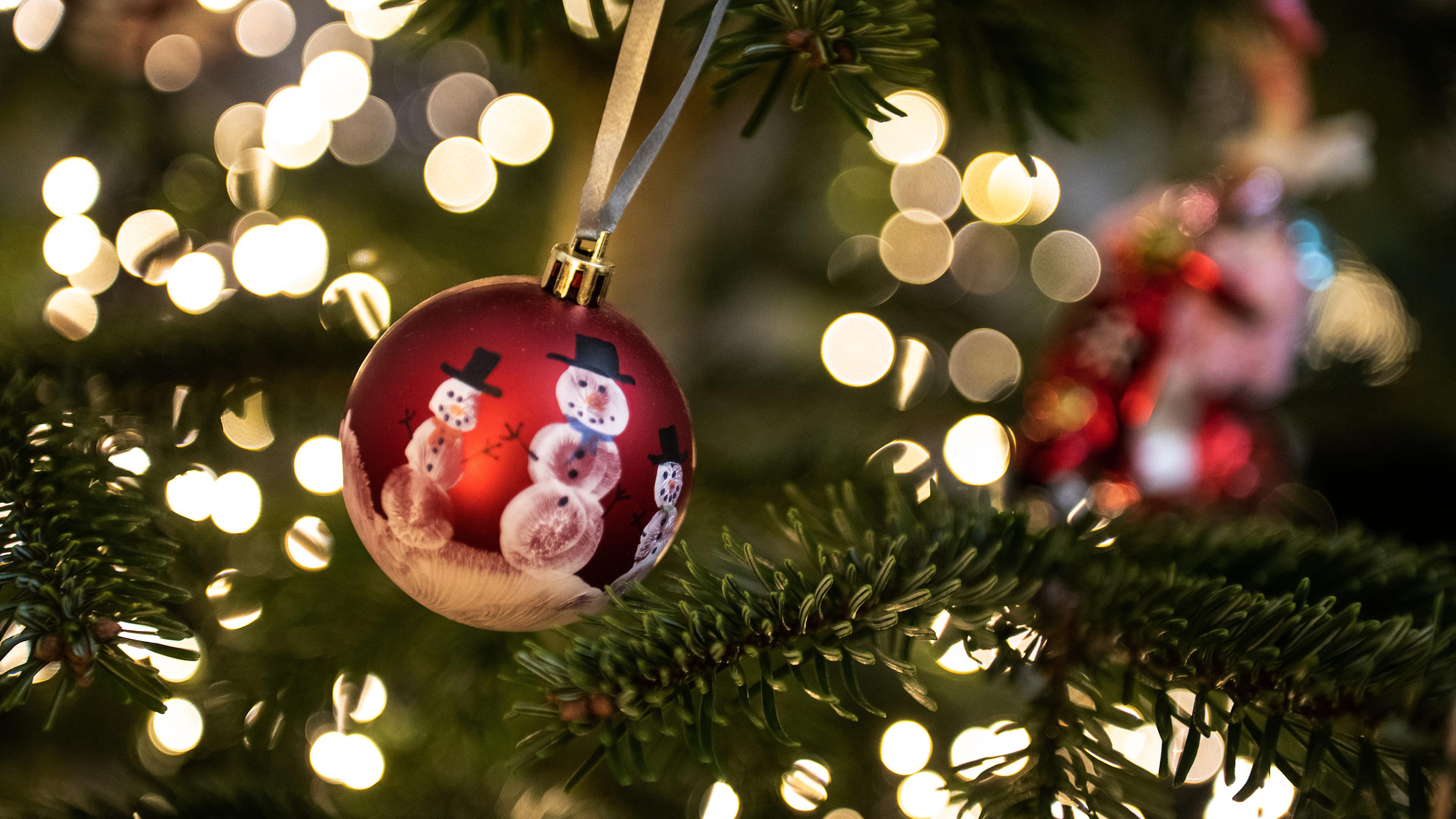 Niedersachsen, Göttingen: Eine Weihnachtskugel hängt an einem Weihnachtsbaum mit einer Lichterkette.