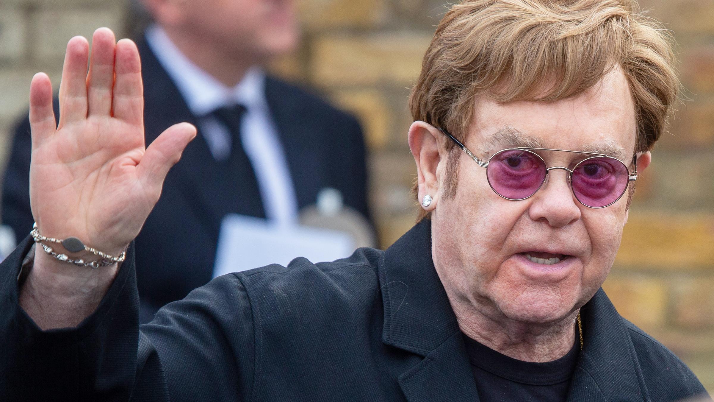 Der Sänger Elton John mit lila Sonnenbrille.