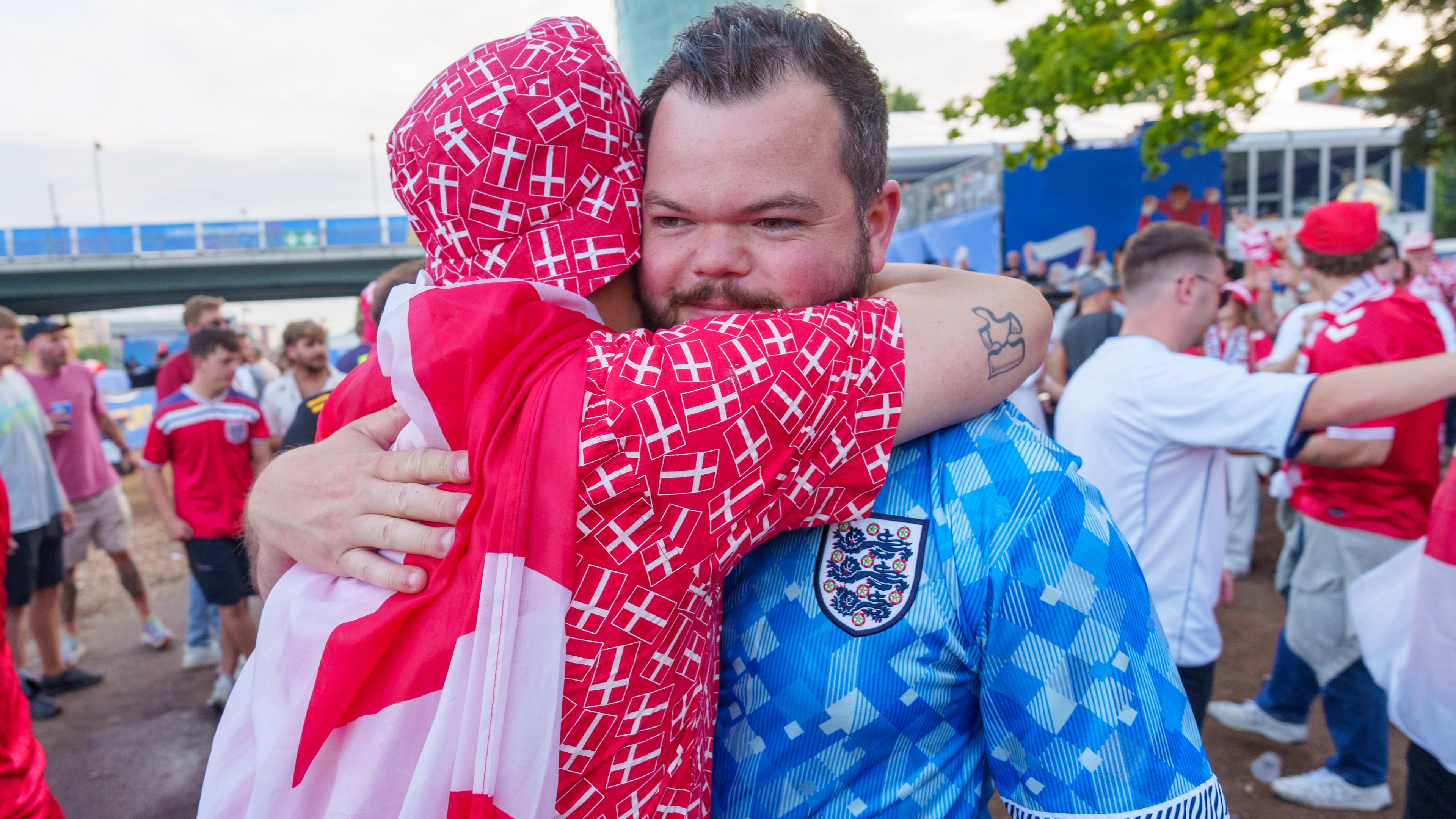 Ein dänischer und ein englischer Fan nehmen sich nach der Begegnung in der Fan-Zone in den Arm.