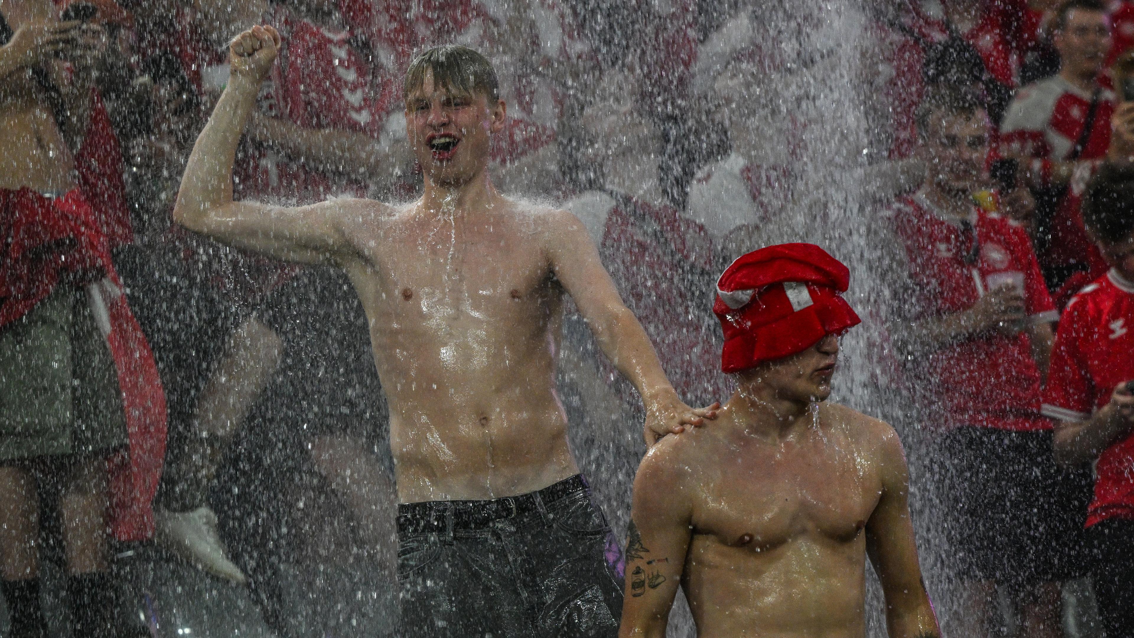Fans von Dänemark tanzen im Regen während einer Spielunterbrechung wegen schlechten Wetters